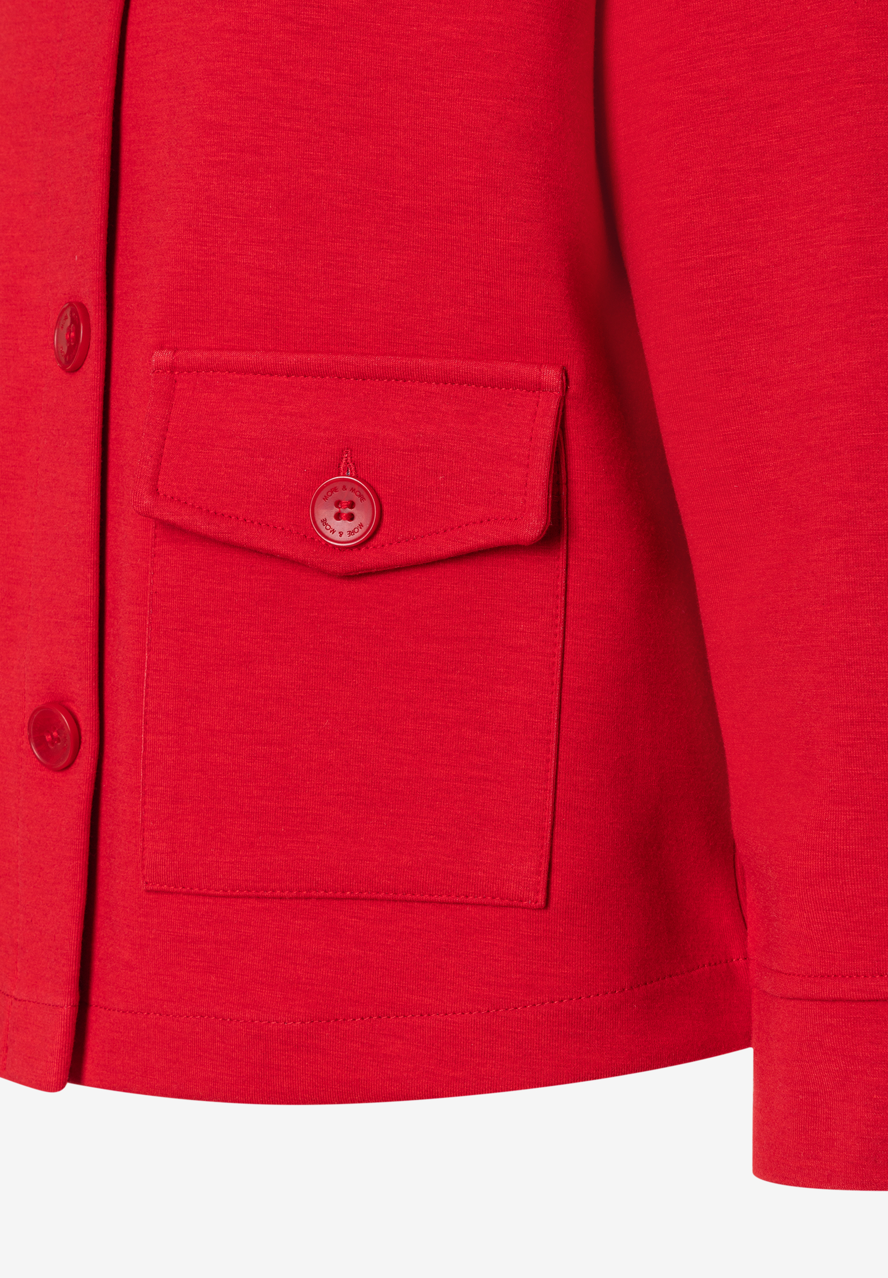 Nahaufnahme eines roten Blazers von MORE & MORE mit Knopfleiste und aufgesetzter Brusttasche. Nahaufnahme eines roten Blazers von MORE & MORE mit Knopfleiste und aufgesetzter Brusttasche.