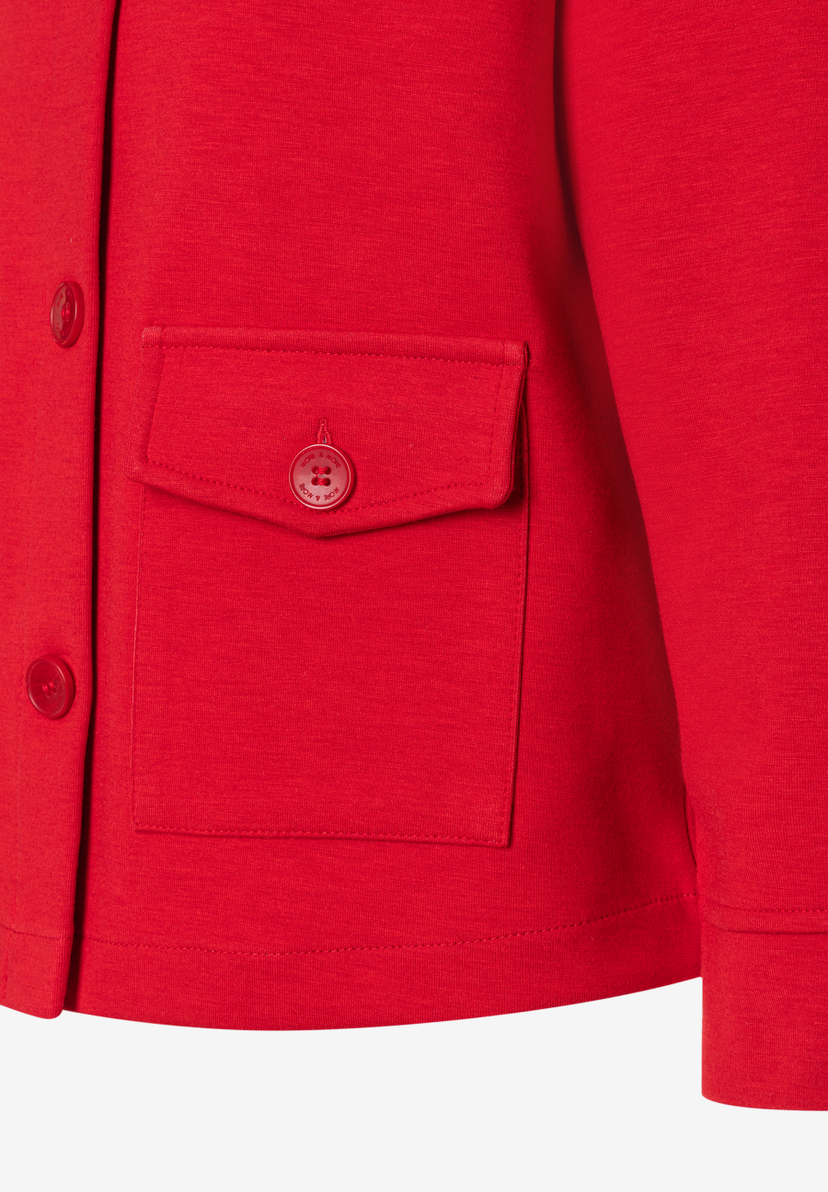 Nahaufnahme eines roten Blazers von MORE & MORE mit Knopfleiste und aufgesetzter Brusttasche. Nahaufnahme eines roten Blazers von MORE & MORE mit Knopfleiste und aufgesetzter Brusttasche.