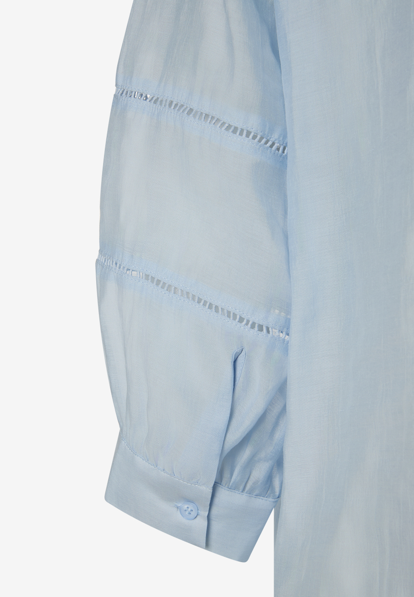 Detailaufnahme einer hellblauen MORE & MORE Bluse mit Lochmuster am Ärmel. Detailaufnahme einer hellblauen MORE & MORE Bluse mit Lochmuster am Ärmel.