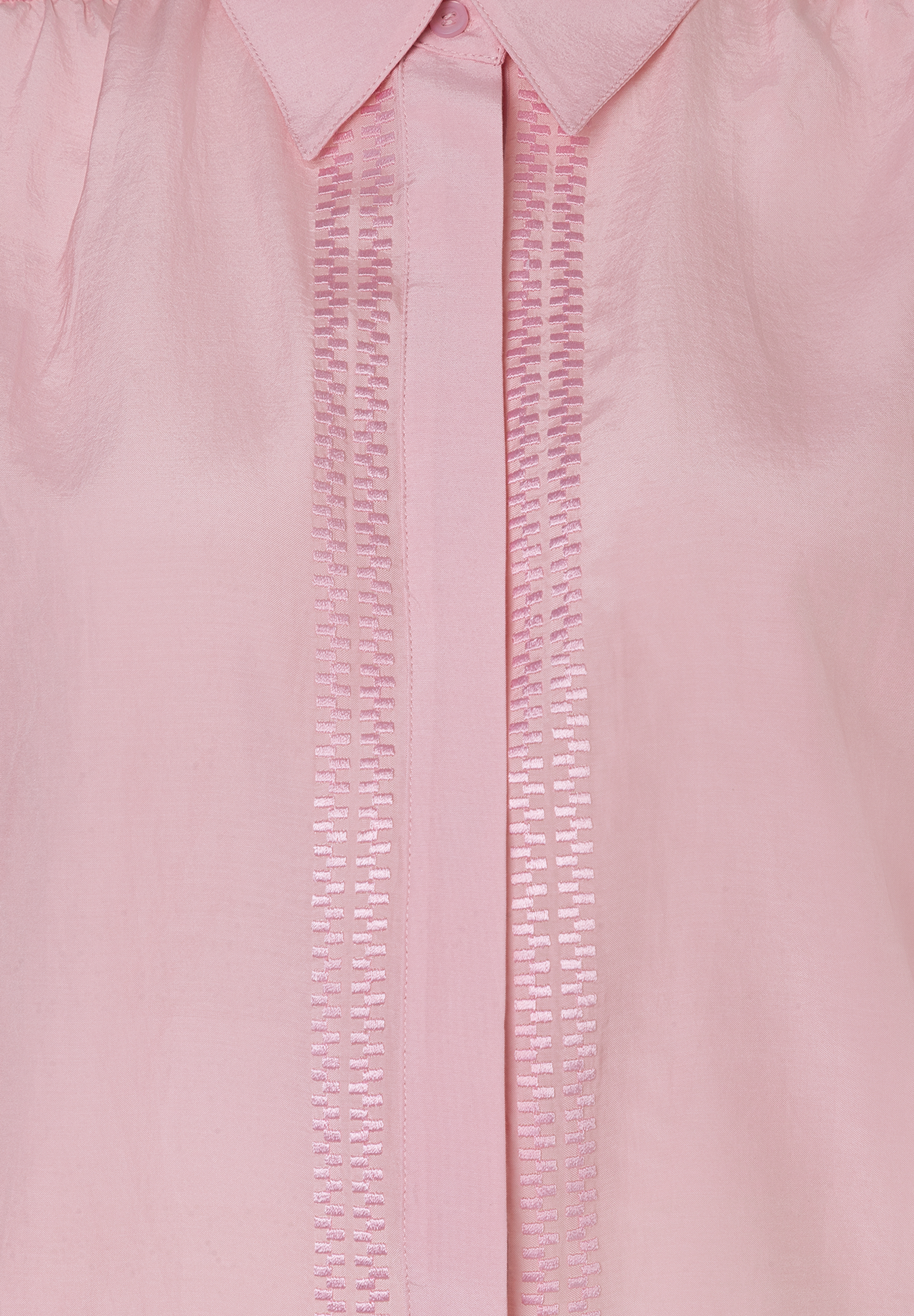 Detailaufnahme einer rosa MORE & MORE Bluse mit Knopf und dekorativen Stickereien. Das Material ist leicht und hautfreundlich. Detailaufnahme einer rosa MORE & MORE Bluse mit Knopf und dekorativen Stickereien. Das Material ist leicht und hautfreundlich.