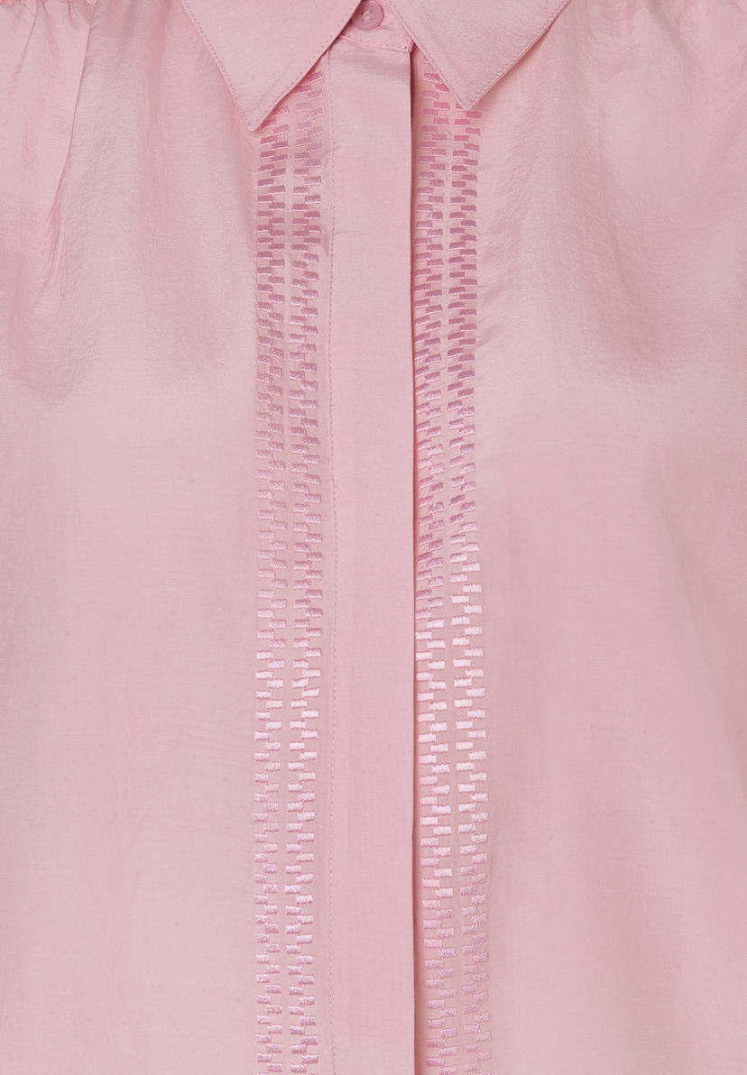 Detailaufnahme einer rosa MORE & MORE Bluse mit Knopf und dekorativen Stickereien. Das Material ist leicht und hautfreundlich. Detailaufnahme einer rosa MORE & MORE Bluse mit Knopf und dekorativen Stickereien. Das Material ist leicht und hautfreundlich.