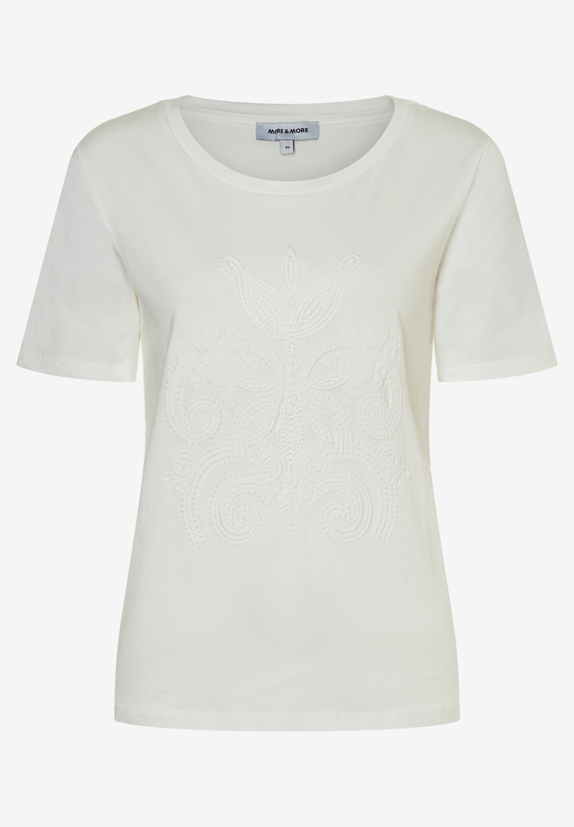 Ein weißes Jersey-T-Shirt von MORE & MORE mit kurzem Arm und einem aufwendigen, tonalen Muster auf der Vorderseite. Ein weißes Jersey-T-Shirt von MORE & MORE mit kurzem Arm und einem aufwendigen, tonalen Muster auf der Vorderseite.