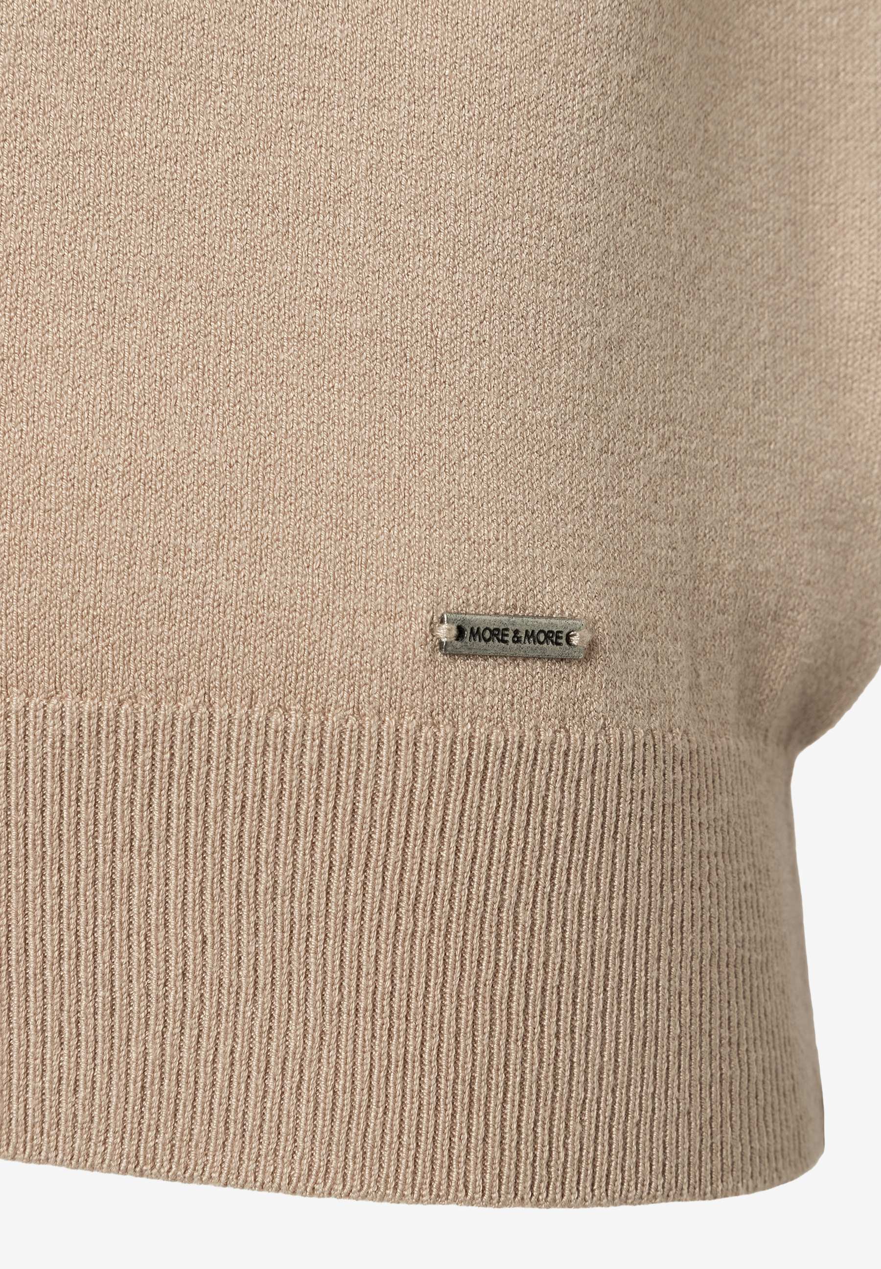 Nahaufnahme von beigem Feinstrick-Oberteil von MORE & MORE mit Logo-Detail. Nahaufnahme von beigem Feinstrick-Oberteil von MORE & MORE mit Logo-Detail.