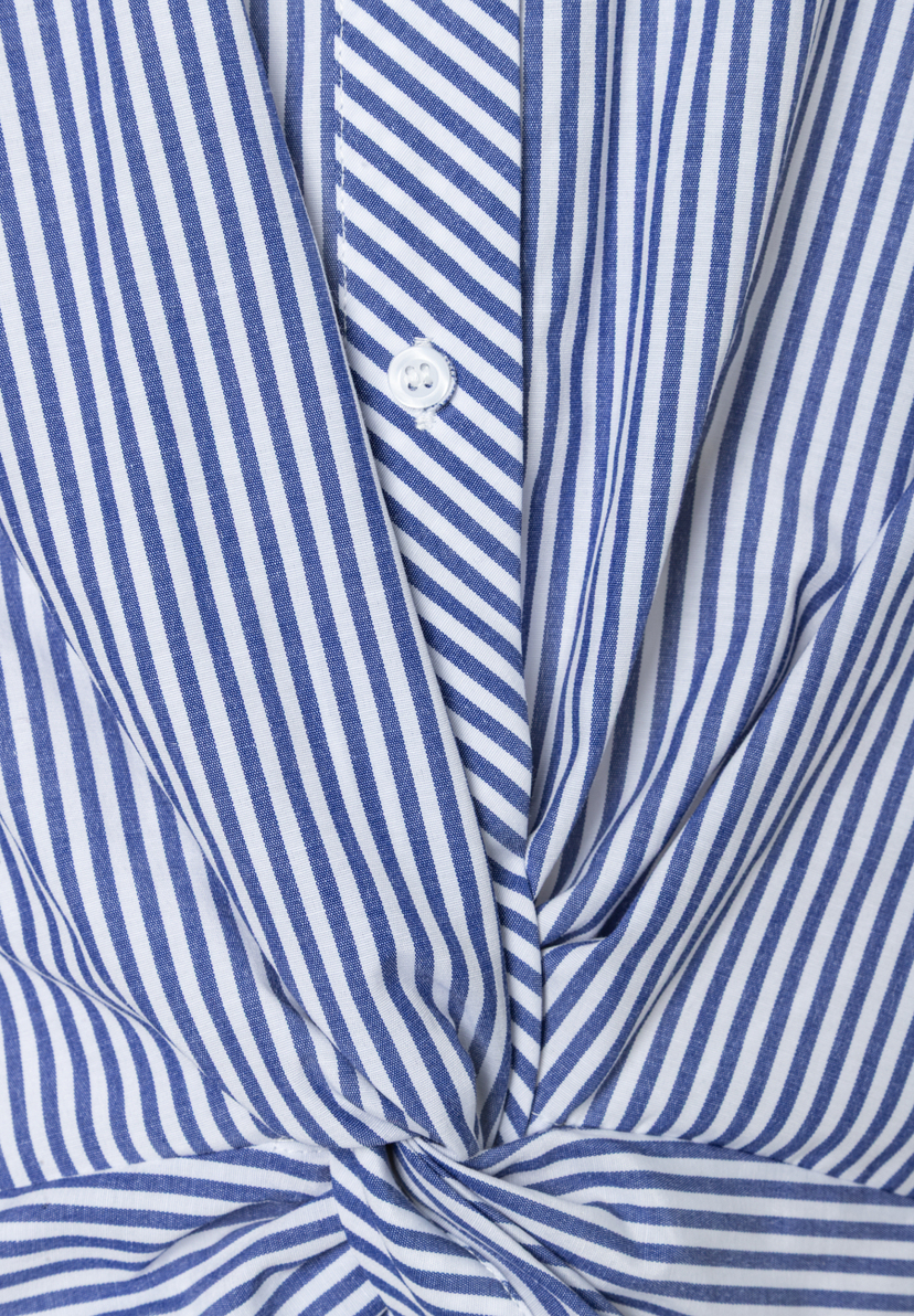 Nahaufnahme einer blau-weiß gestreiften Bluse von MORE & MORE aus Popeline mit Knopf und Knotendetail. Nahaufnahme einer blau-weiß gestreiften Bluse von MORE & MORE aus Popeline mit Knopf und Knotendetail.