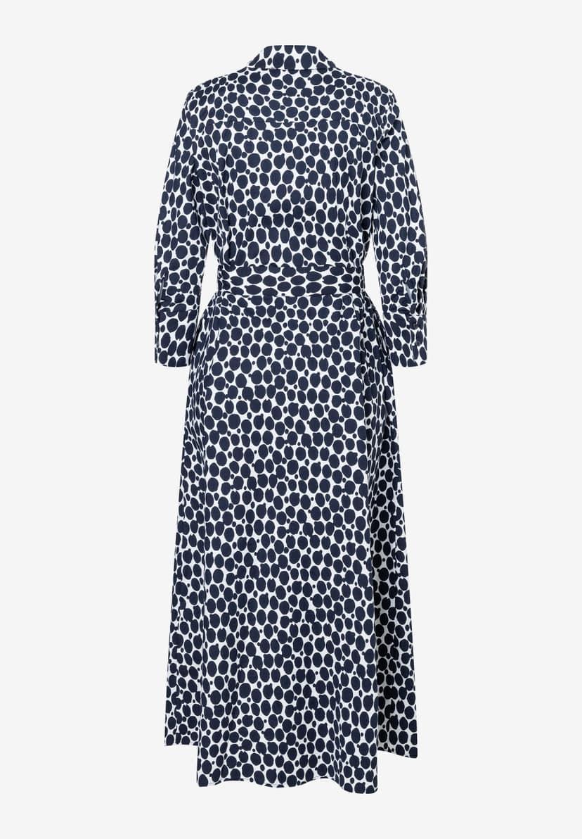 Ein MORE & MORE Kleid mit einem Muster aus dunkelblauen Punkten auf weißem Grund, von hinten fotografiert. Ein MORE & MORE Kleid mit einem Muster aus dunkelblauen Punkten auf weißem Grund, von hinten fotografiert.