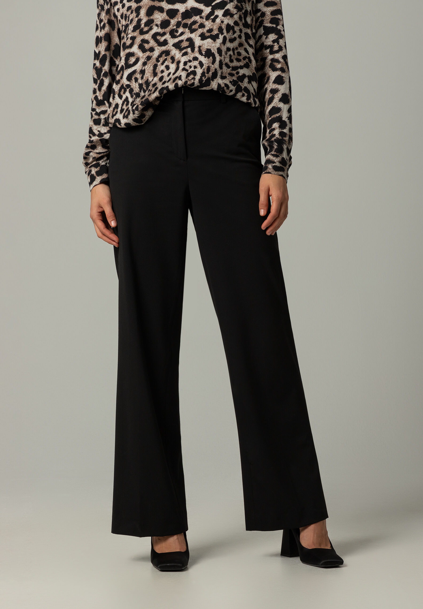 Eine MORE & MORE Hose aus Gabardine-Stretch in Schwarz, kombiniert mit einer Bluse mit Tiermuster.