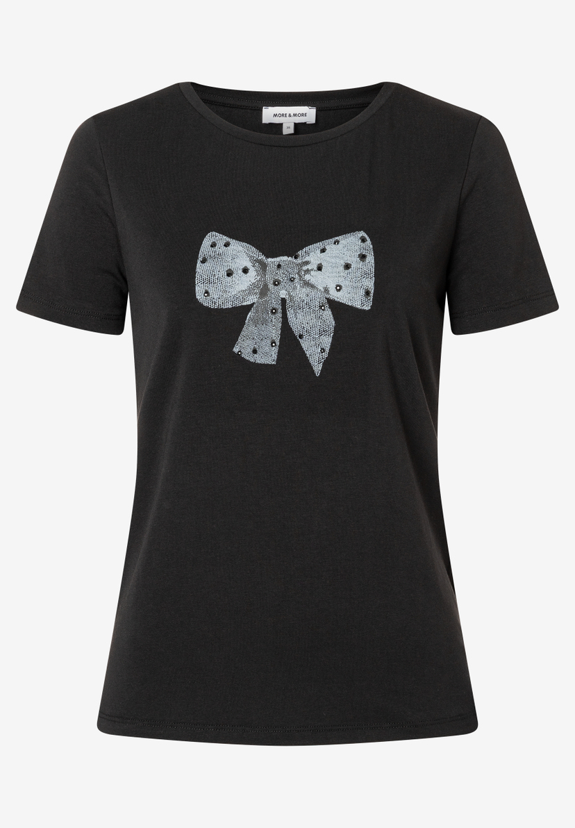 Ein schwarzes T-Shirt von MORE & MORE mit einer großen, glitzernden Schleife auf der Vorderseite. Ein schwarzes T-Shirt von MORE & MORE mit einer großen, glitzernden Schleife auf der Vorderseite.