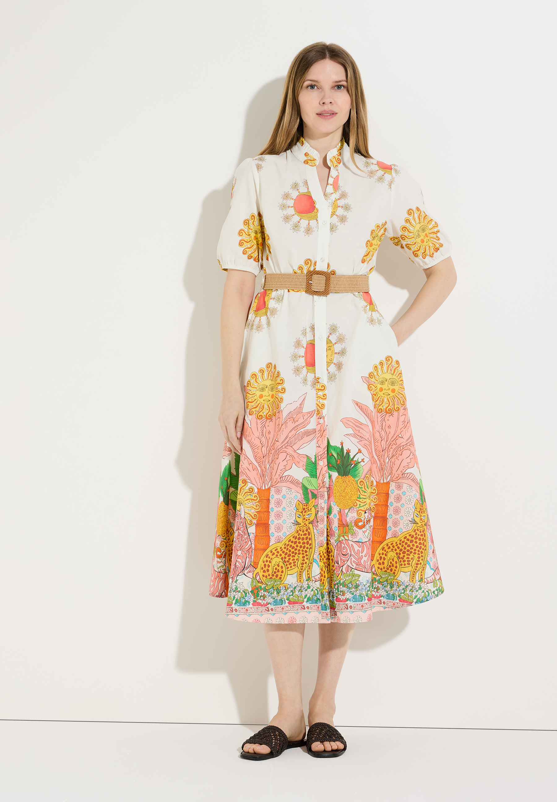 Eine Frau, die ein bedrucktes MORE & MORE Oberteil-Kleid mit Gürtel trägt. Eine Frau, die ein bedrucktes MORE & MORE Oberteil-Kleid mit Gürtel trägt.