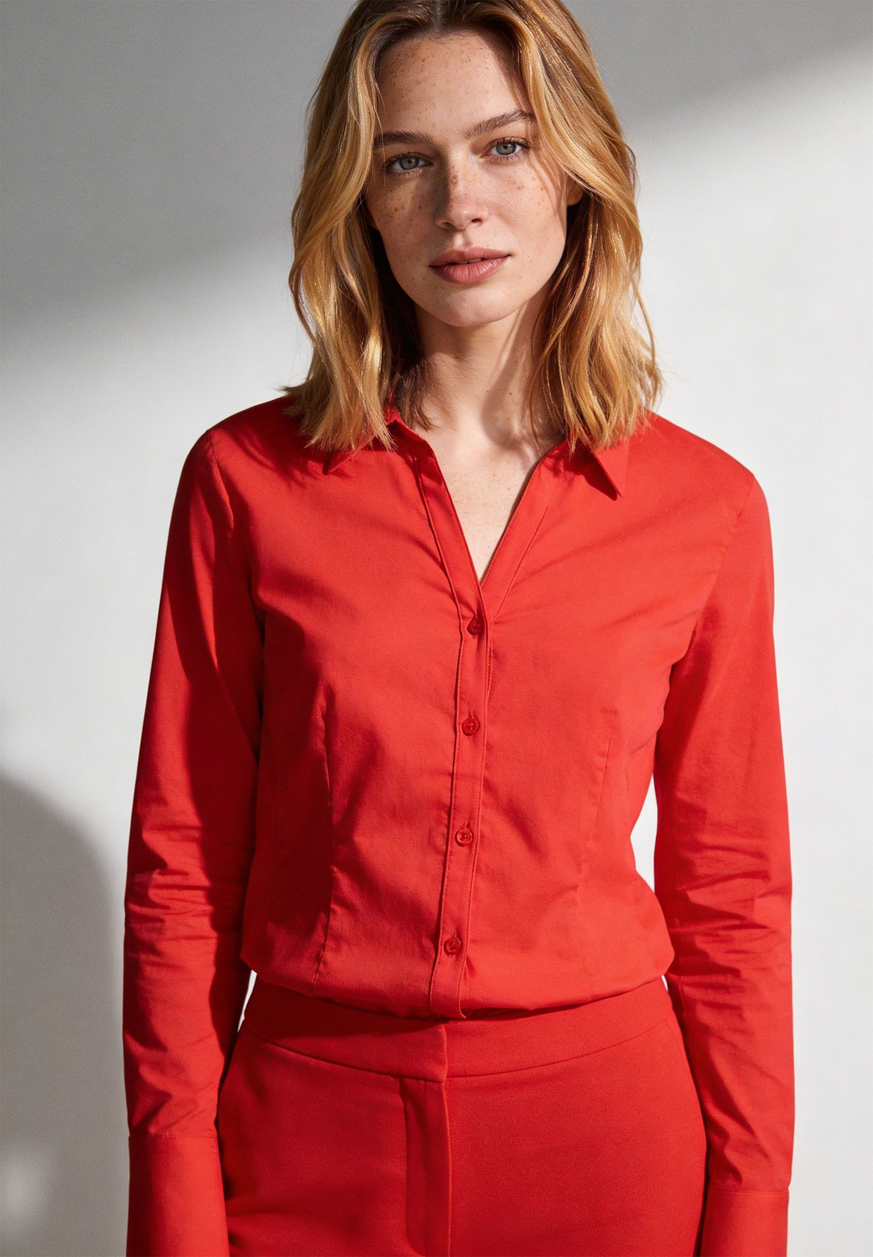 Eine Frau trägt eine rote Bluse von MORE & MORE aus Popeline mit langen Ärmeln. Eine Frau trägt eine rote Bluse von MORE & MORE aus Popeline mit langen Ärmeln.