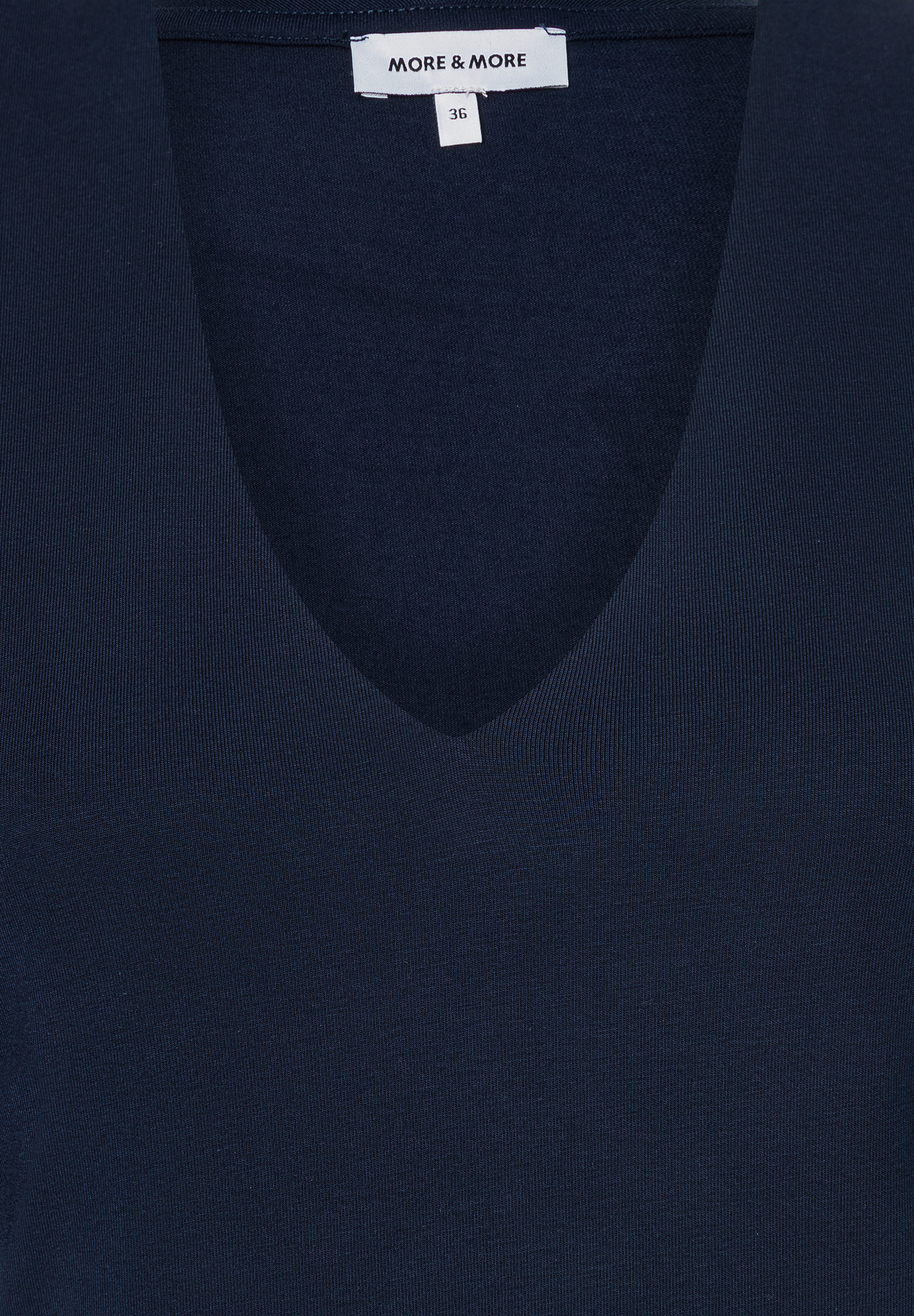 Nahaufnahme eines marineblauen MORE & MORE Oberteils mit V-Ausschnitt und Jersey-Material. Nahaufnahme eines marineblauen MORE & MORE Oberteils mit V-Ausschnitt und Jersey-Material.