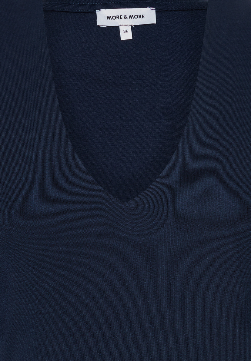Nahaufnahme eines marineblauen MORE & MORE Oberteils mit V-Ausschnitt und Jersey-Material. Nahaufnahme eines marineblauen MORE & MORE Oberteils mit V-Ausschnitt und Jersey-Material.