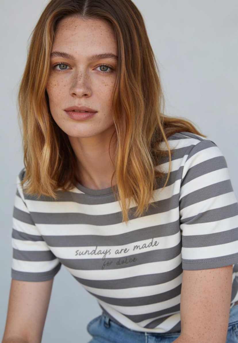 AI generated - Eine Frau mit Sommersprossen trägt ein gestreiftes T-Shirt von MORE & MORE mit der Aufschrift "sundays are made for dolce". AI generated - Eine Frau mit Sommersprossen trägt ein gestreiftes T-Shirt von MORE & MORE mit der Aufschrift "sundays are made for dolce".