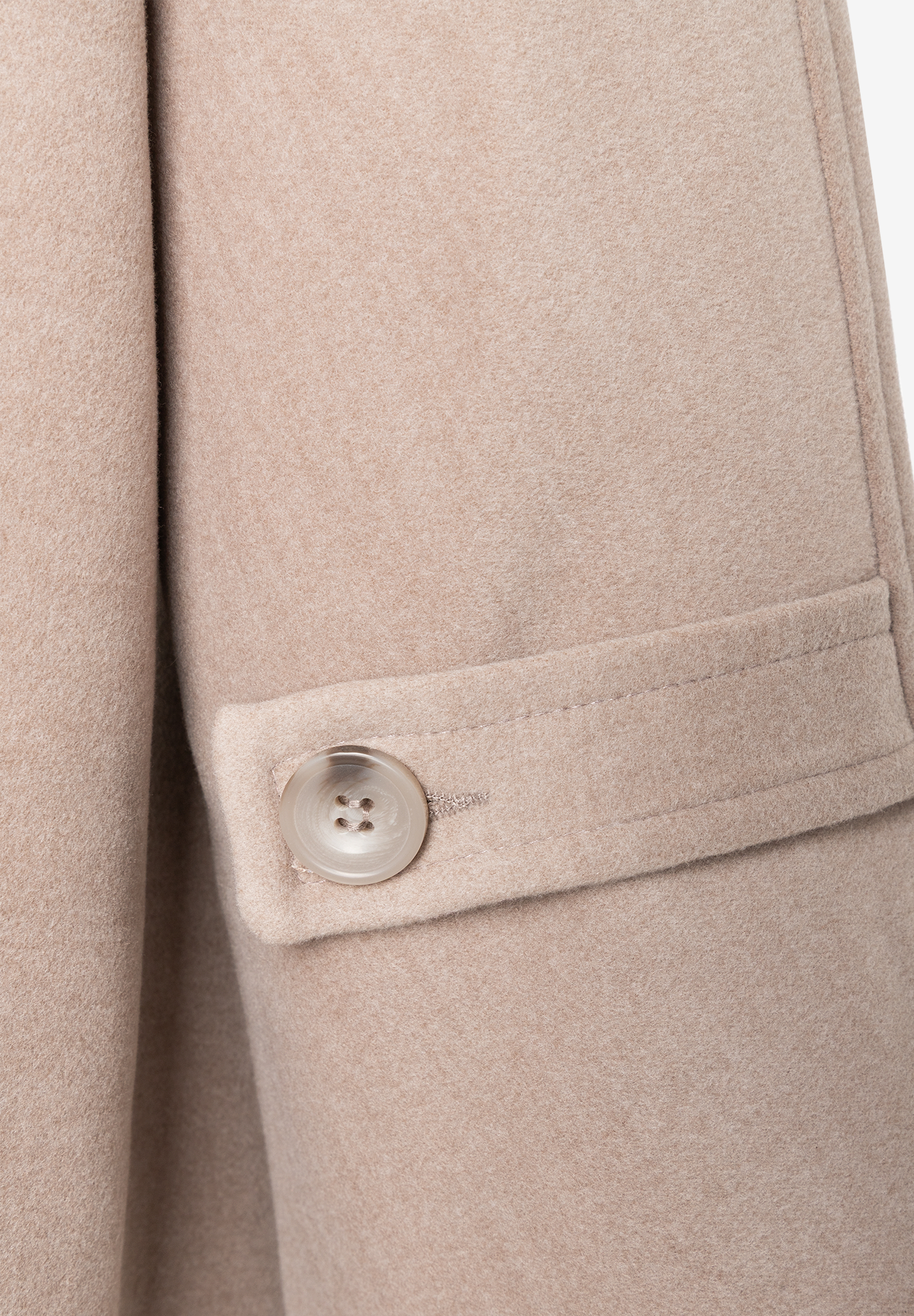 MORE & MORE Jacke: Nahaufnahme eines beigen Mantels mit einem transparenten, gemusterten Knopf an der Manschette. MORE & MORE Jacke: Nahaufnahme eines beigen Mantels mit einem transparenten, gemusterten Knopf an der Manschette.