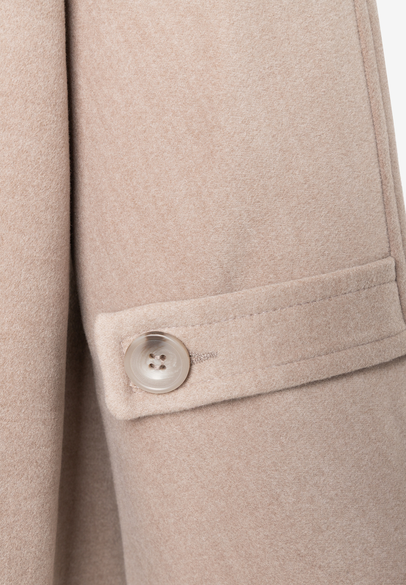 MORE & MORE Jacke: Nahaufnahme eines beigen Mantels mit einem transparenten, gemusterten Knopf an der Manschette. MORE & MORE Jacke: Nahaufnahme eines beigen Mantels mit einem transparenten, gemusterten Knopf an der Manschette.
