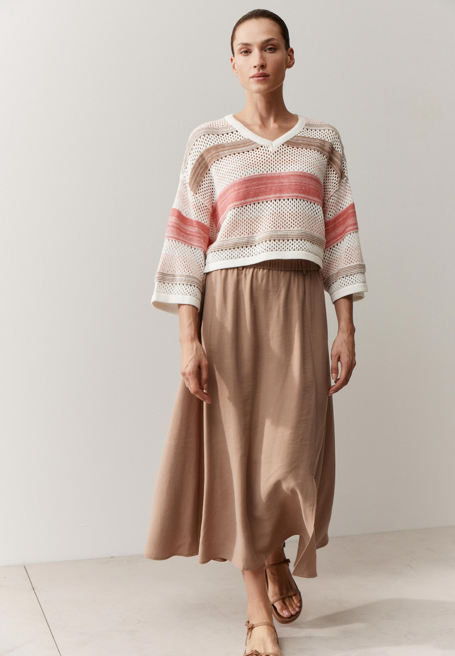 Eine Frau trägt ein MORE & MORE Oberteil (Pullovers-Knitwear) mit beiger, langer Rock und Sandalen. Eine Frau trägt ein MORE & MORE Oberteil (Pullovers-Knitwear) mit beiger, langer Rock und Sandalen.