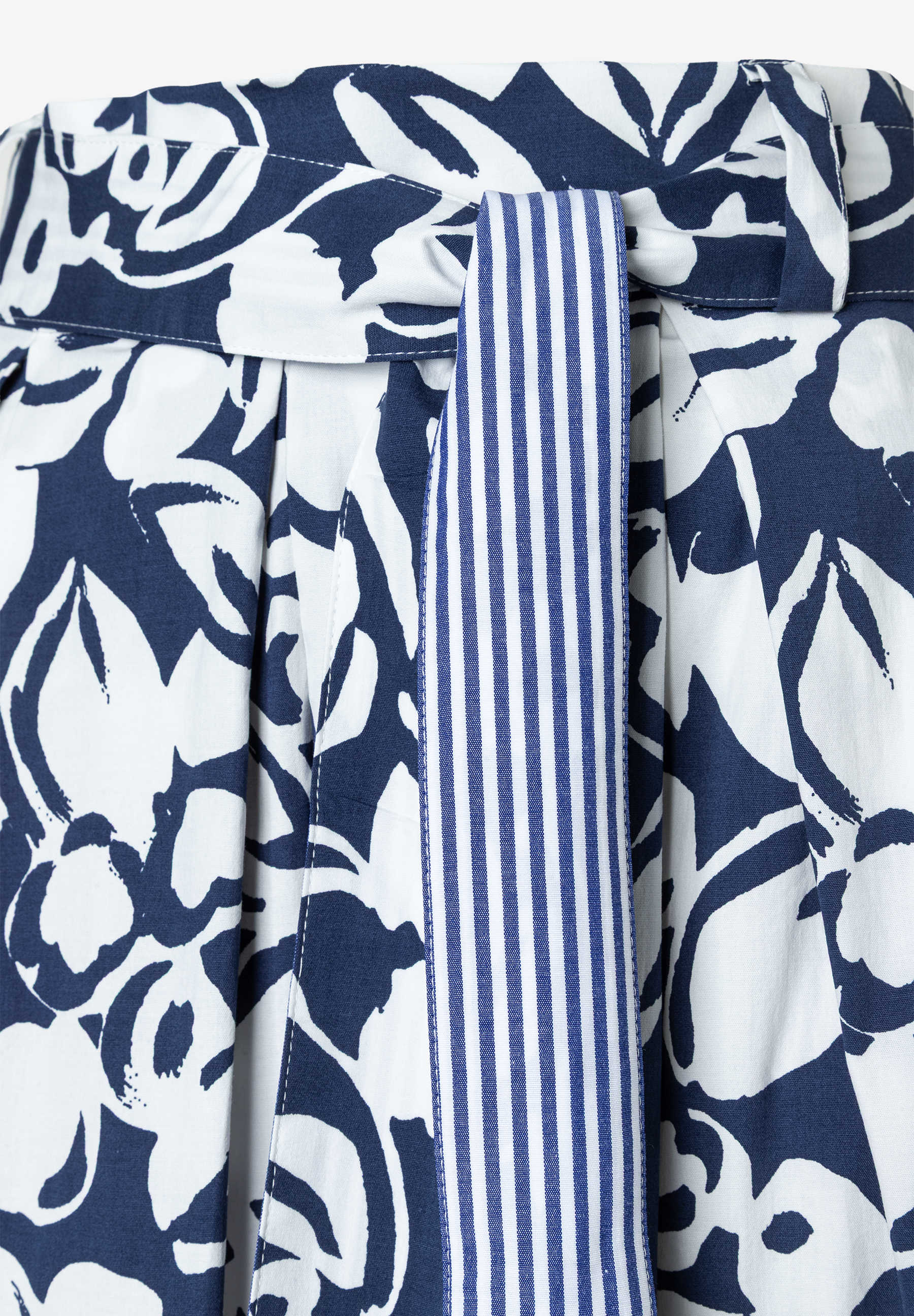 Detailansicht eines Rockes von MORE & MORE mit blau-weißem Blumenmuster und einem blau-weiß gestreiften Gürtel. Detailansicht eines Rockes von MORE & MORE mit blau-weißem Blumenmuster und einem blau-weiß gestreiften Gürtel.