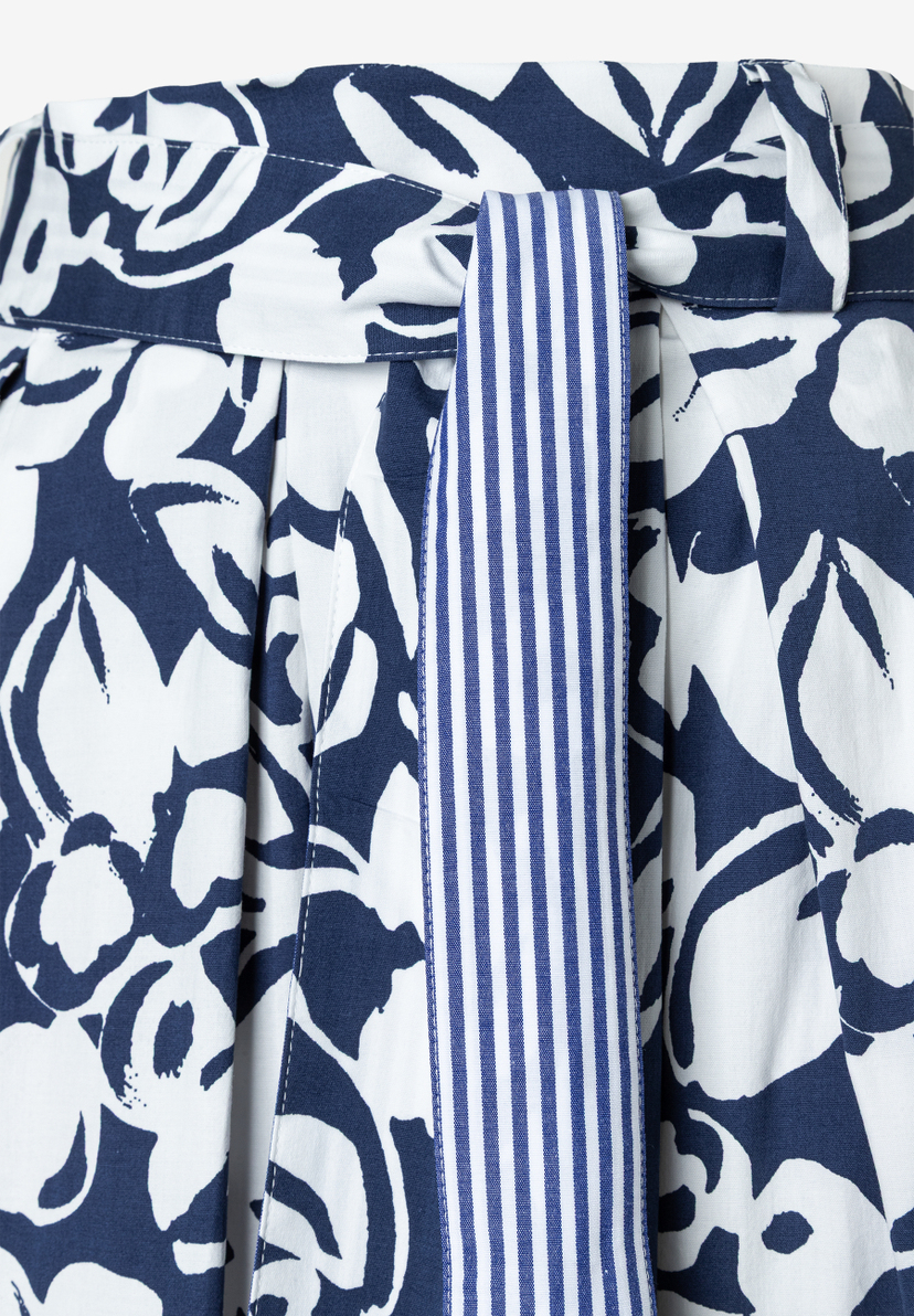 Detailansicht eines Rockes von MORE & MORE mit blau-weißem Blumenmuster und einem blau-weiß gestreiften Gürtel. Detailansicht eines Rockes von MORE & MORE mit blau-weißem Blumenmuster und einem blau-weiß gestreiften Gürtel.