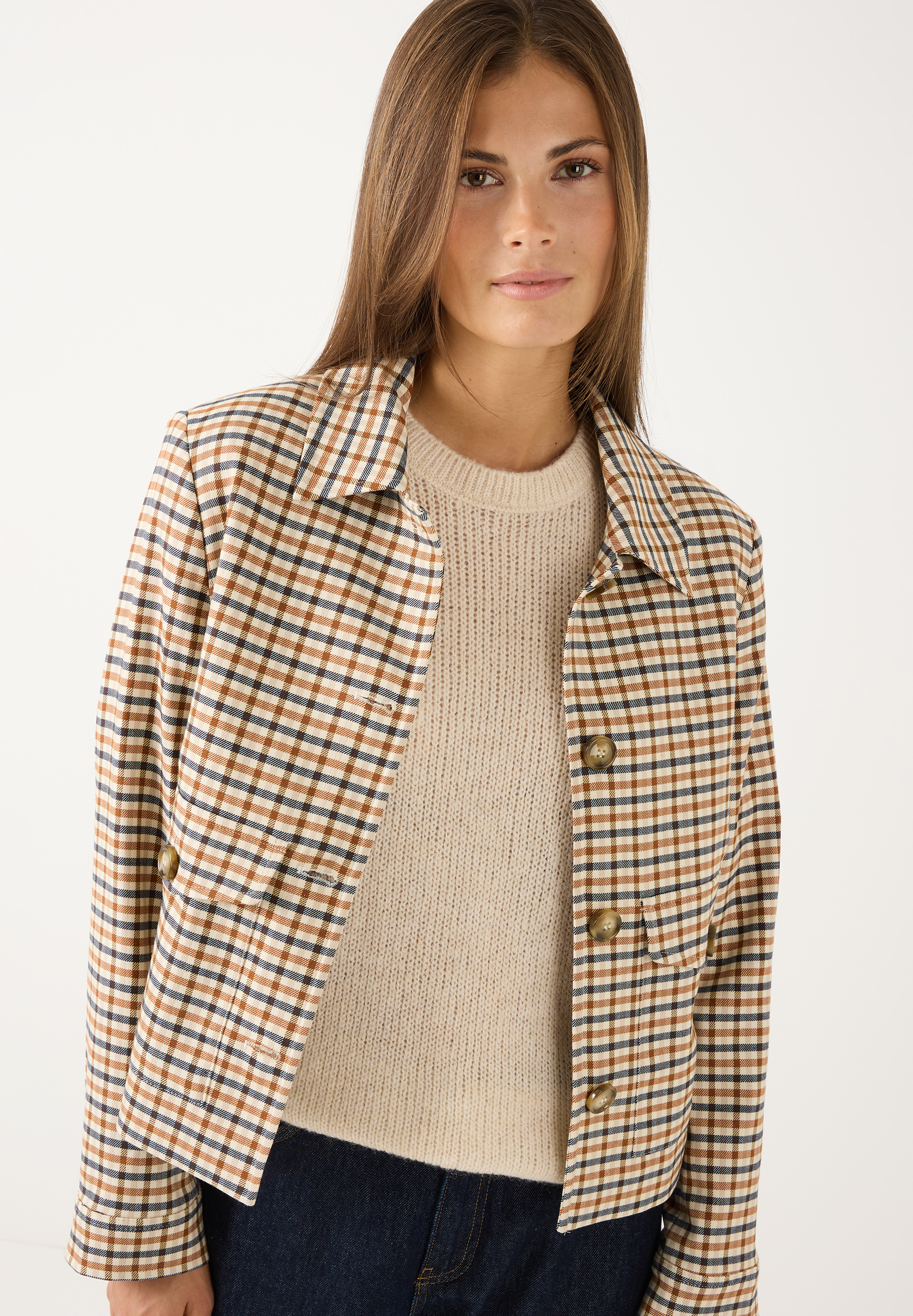 MORE & MORE Blazer: Eine Frau trägt einen karierten Blazer in Braun, Blau und Beige über einem beigefarbenen Strickpullover.