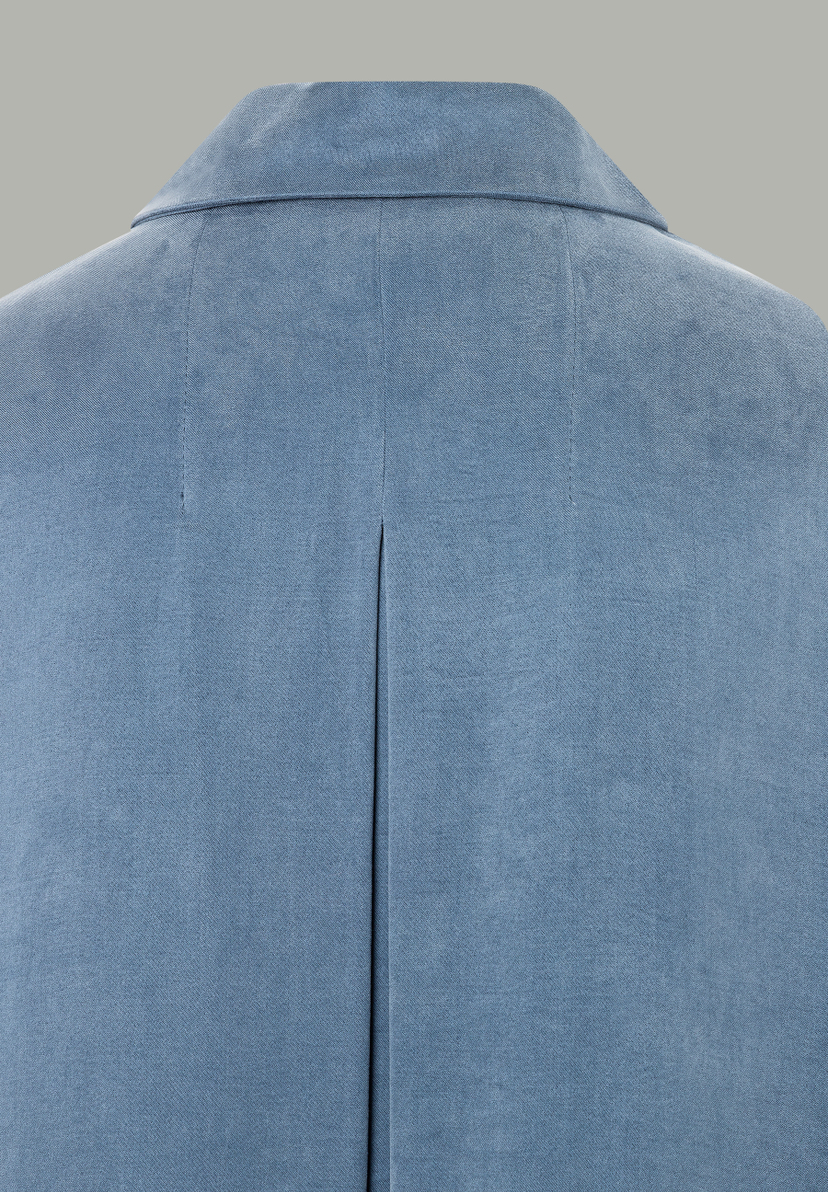 Nahaufnahme der Rückenpartie einer hellblauen MORE & MORE Bluse mit Kragen und Falte. Nahaufnahme der Rückenpartie einer hellblauen MORE & MORE Bluse mit Kragen und Falte.