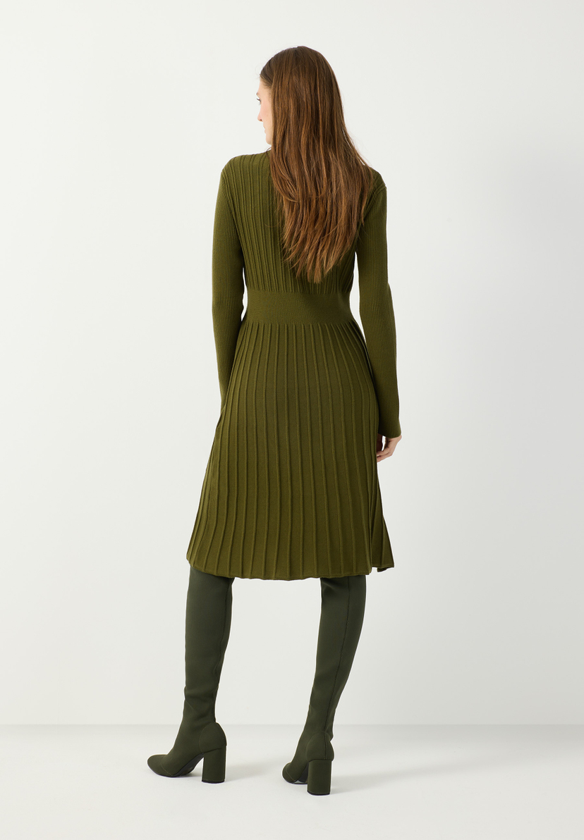 MORE & MORE grünes Rippstrick-Kleid. Eine junge Frau mit langen braunen Haaren posiert mit Blick nach links. MORE & MORE grünes Rippstrick-Kleid. Eine junge Frau mit langen braunen Haaren posiert mit Blick nach links.