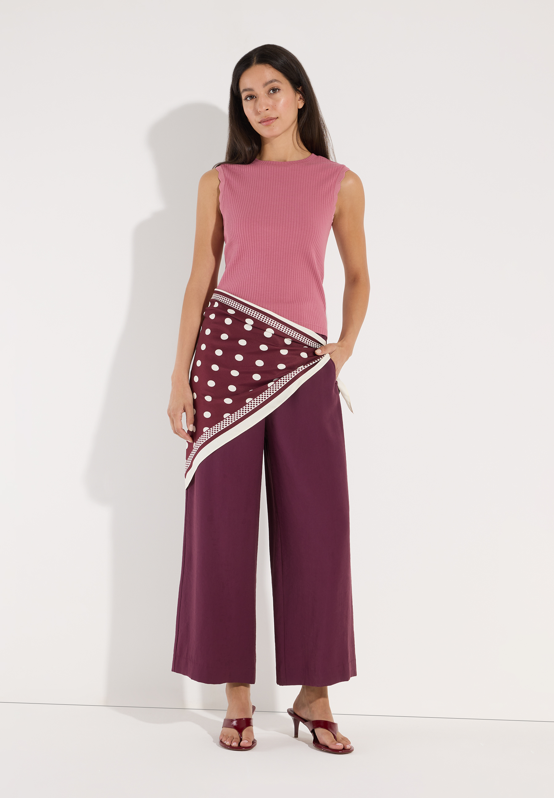 MORE & MORE geripptes Top in Rosa kombiniert mit weinroter Hose und passenden Schuhen, Model posiert. MORE & MORE geripptes Top in Rosa kombiniert mit weinroter Hose und passenden Schuhen, Model posiert.