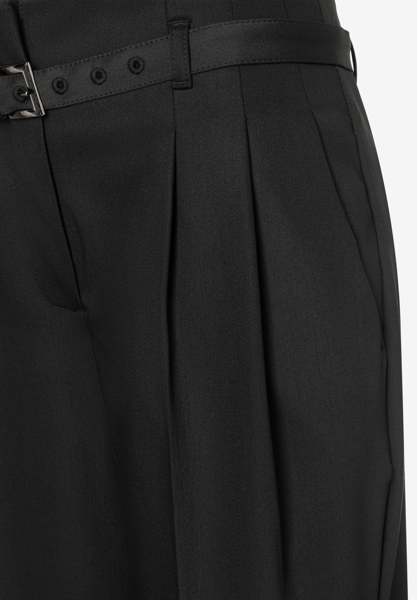 Nahaufnahme einer schwarzen MORE & MORE Hose mit Bundfalten und Gürtel. Nahaufnahme einer schwarzen MORE & MORE Hose mit Bundfalten und Gürtel.