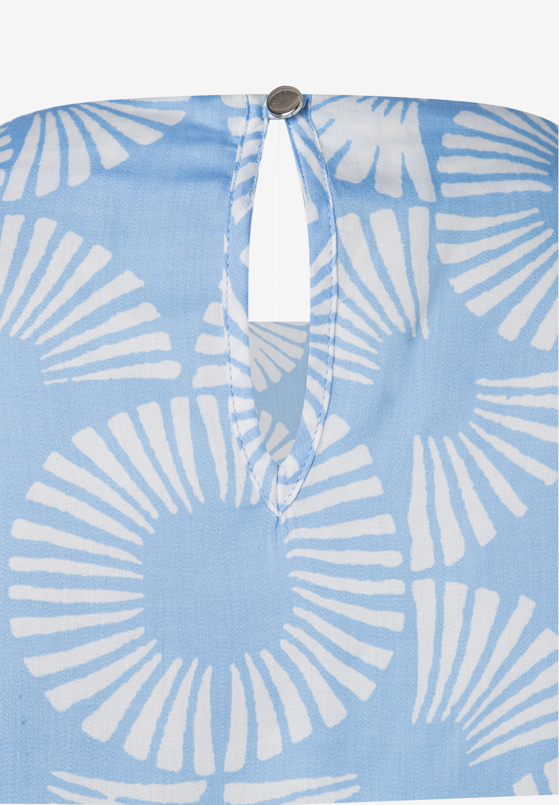 Nahaufnahme einer hellblauen MORE & MORE Bluse mit weißem Muster und einem Knopf am Halsausschnitt. Nahaufnahme einer hellblauen MORE & MORE Bluse mit weißem Muster und einem Knopf am Halsausschnitt.