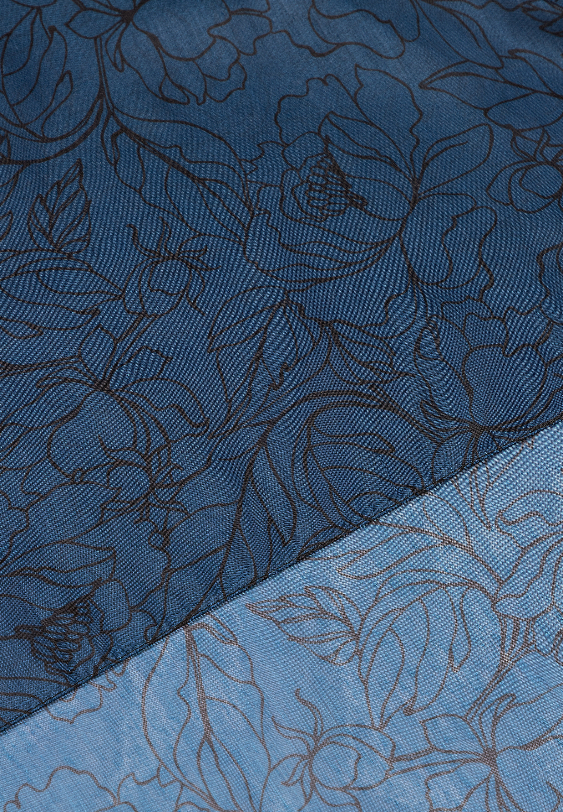 Nahaufnahme eines MORE & MORE Accessoires mit floralem Muster in Blau, geteilt durch eine Naht. Nahaufnahme eines MORE & MORE Accessoires mit floralem Muster in Blau, geteilt durch eine Naht.