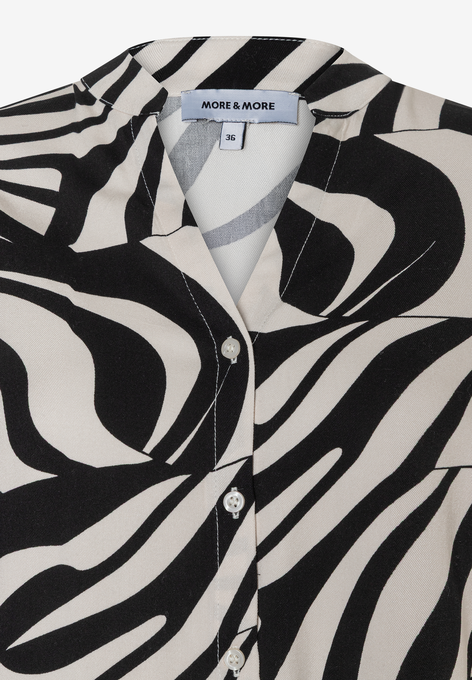 Nahaufnahme einer MORE & MORE Bluse mit auffälligem Zebra-Muster und Knopfleiste. Nahaufnahme einer MORE & MORE Bluse mit auffälligem Zebra-Muster und Knopfleiste.