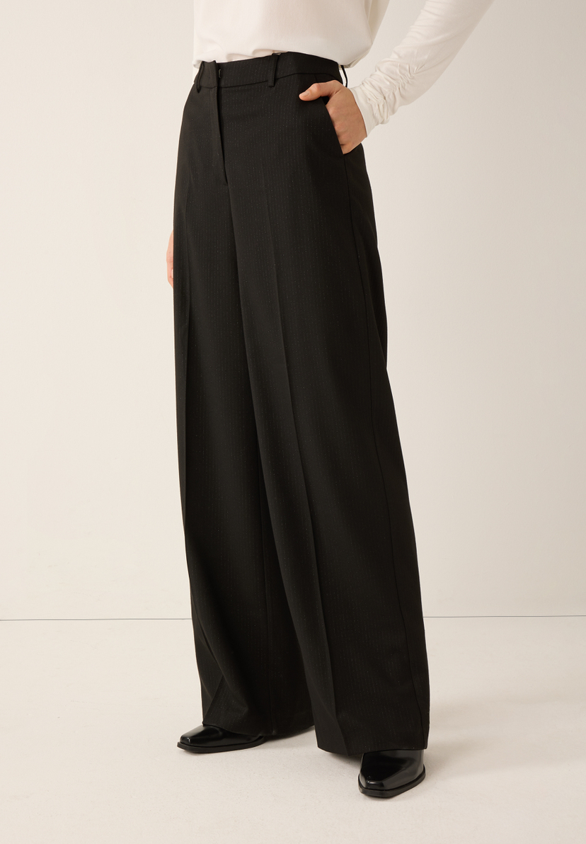 Eine Person trägt eine schwarze Webware Hose von MORE & MORE, kombiniert mit High Heels. Eine Person trägt eine schwarze Webware Hose von MORE & MORE, kombiniert mit High Heels.