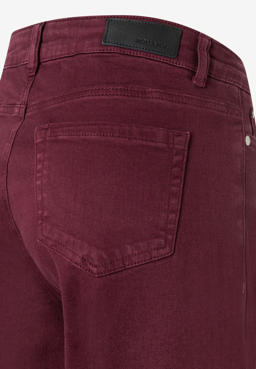 Nahaufnahme der Rückseite einer weinroten Denim-Jeans von MORE & MORE mit Gesäßtasche und Markenlabel. Nahaufnahme der Rückseite einer weinroten Denim-Jeans von MORE & MORE mit Gesäßtasche und Markenlabel.