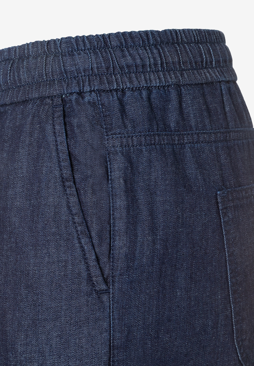 Detailansicht einer MORE & MORE Denimhose mit elastischem Bund und Seitentasche.