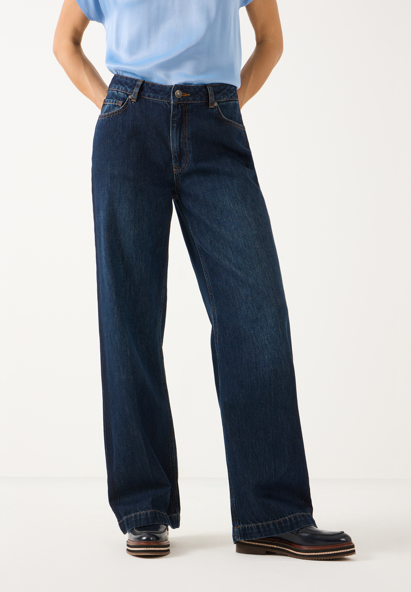 MORE & MORE Jeans: eine Person in dunkelblauer Denim-Jeans mit weitem Bein und hellem Oberteil, Hände in Hosentaschen. MORE & MORE Jeans: eine Person in dunkelblauer Denim-Jeans mit weitem Bein und hellem Oberteil, Hände in Hosentaschen.