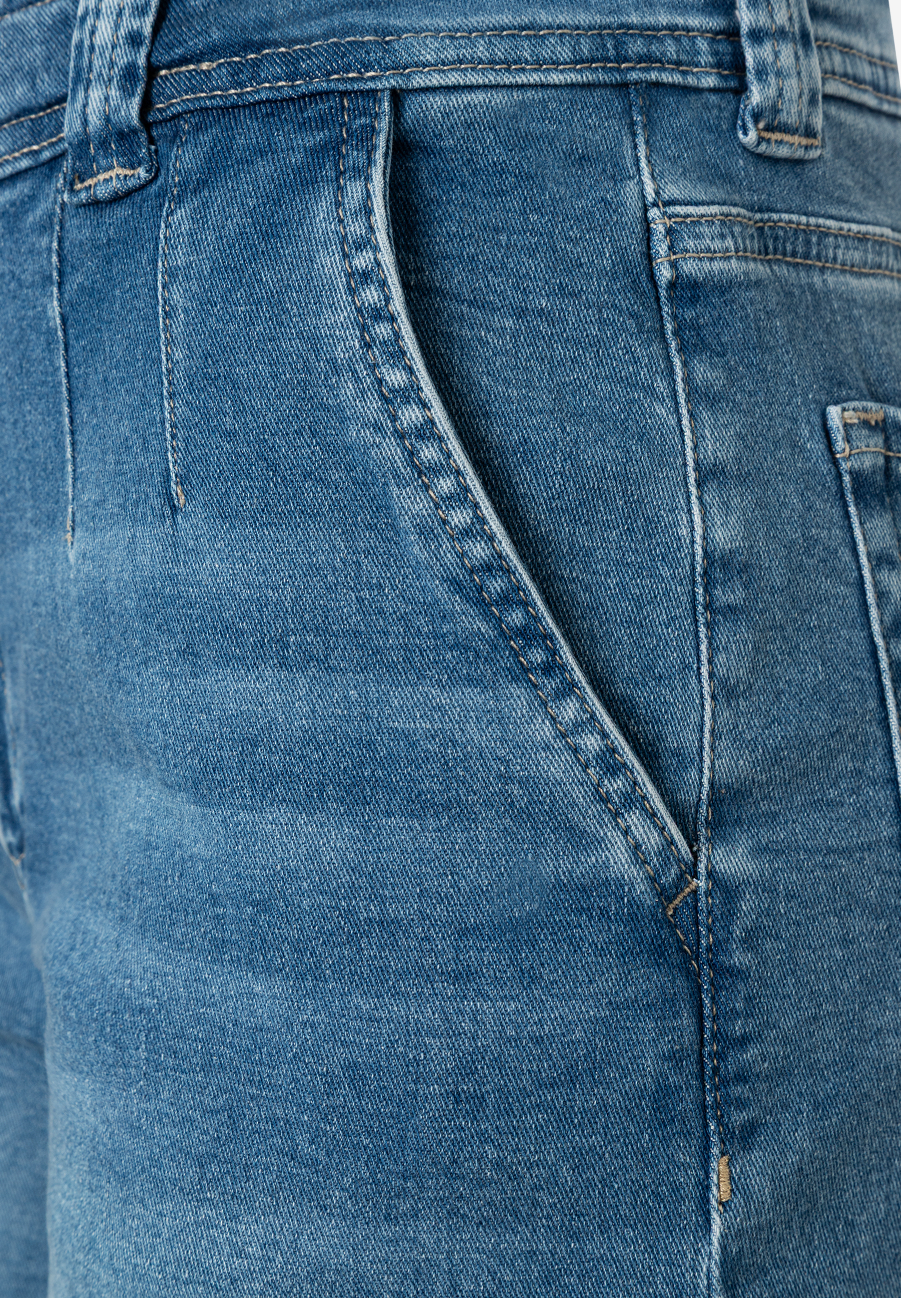 Nahaufnahme einer blauen MORE & MORE Jeans mit schräg verlaufender, abgesteppter Vordertasche. Nahaufnahme einer blauen MORE & MORE Jeans mit schräg verlaufender, abgesteppter Vordertasche.