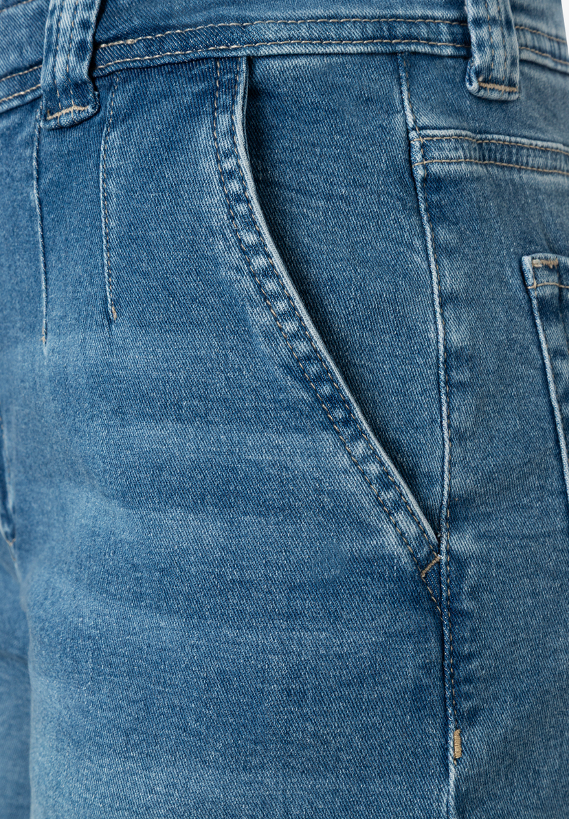Nahaufnahme einer blauen MORE & MORE Jeans mit schräg verlaufender, abgesteppter Vordertasche. Nahaufnahme einer blauen MORE & MORE Jeans mit schräg verlaufender, abgesteppter Vordertasche.