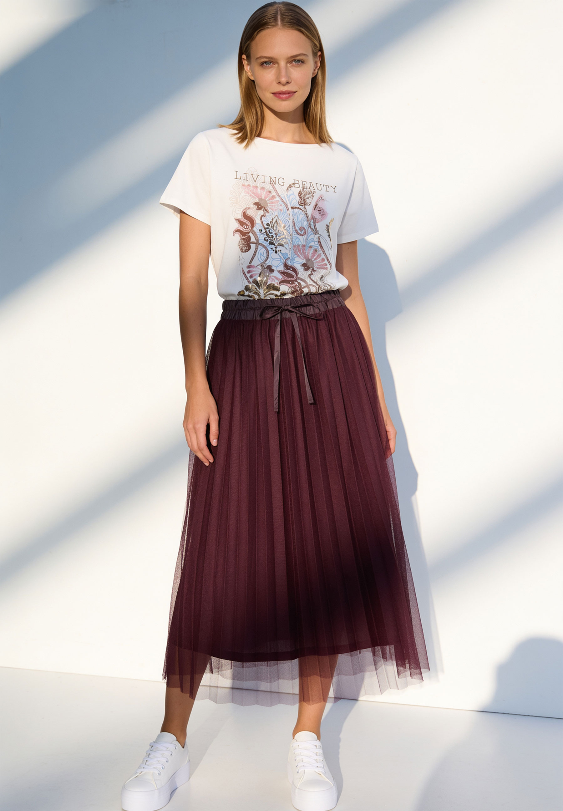 MORE & MORE Midirock aus Mesh in Aubergine mit Bund zum Binden und Falten, dazu ein weißes T-Shirt und Sneaker. MORE & MORE Midirock aus Mesh in Aubergine mit Bund zum Binden und Falten, dazu ein weißes T-Shirt und Sneaker.