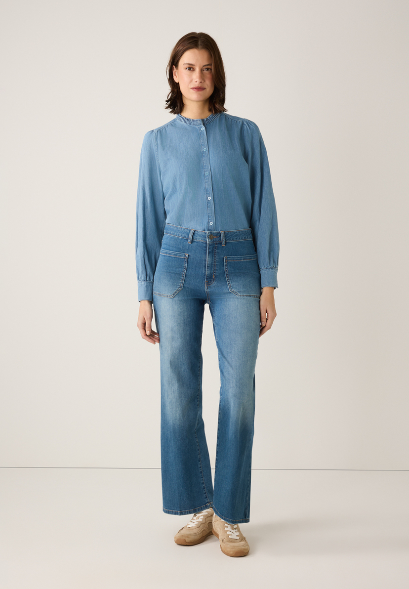 Eine Frau in MORE & MORE Denim-Bluse mit langen Ärmeln und Jeans. Angenehmer Tragekomfort und hautfreundlich. Eine Frau in MORE & MORE Denim-Bluse mit langen Ärmeln und Jeans. Angenehmer Tragekomfort und hautfreundlich.