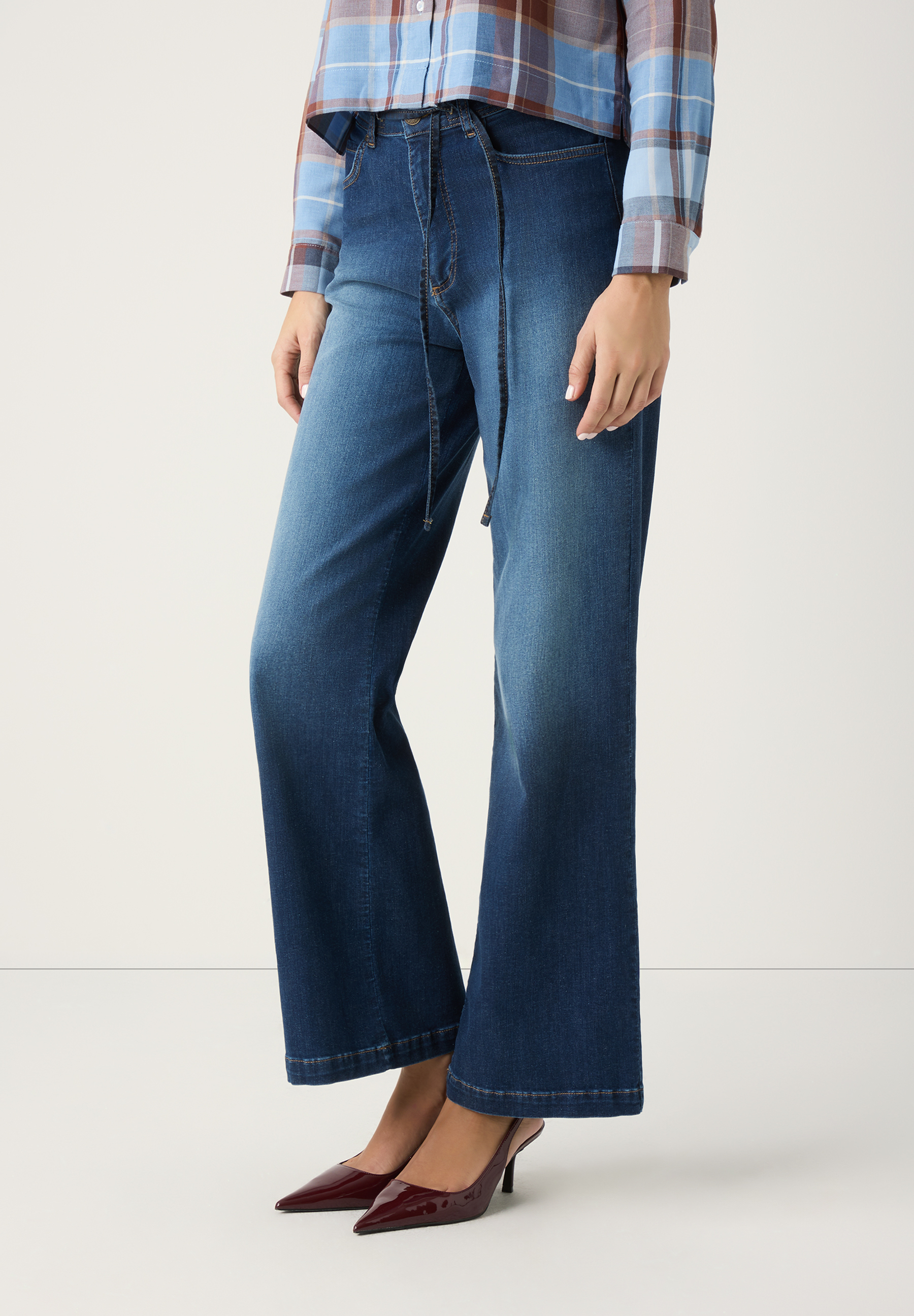 Eine Frau trägt MORE & MORE Jeans aus Denim mit weitem Bein und braune Lackschuhe. Eine Frau trägt MORE & MORE Jeans aus Denim mit weitem Bein und braune Lackschuhe.