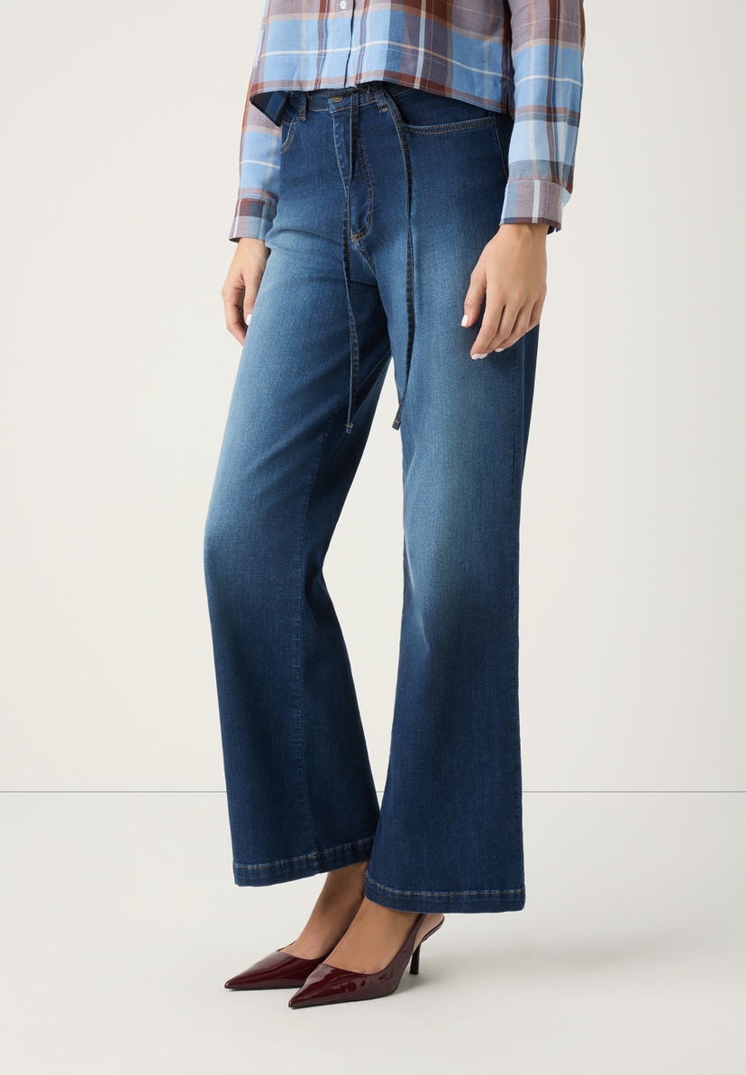 Eine Frau trägt MORE & MORE Jeans aus Denim mit weitem Bein und braune Lackschuhe. Eine Frau trägt MORE & MORE Jeans aus Denim mit weitem Bein und braune Lackschuhe.