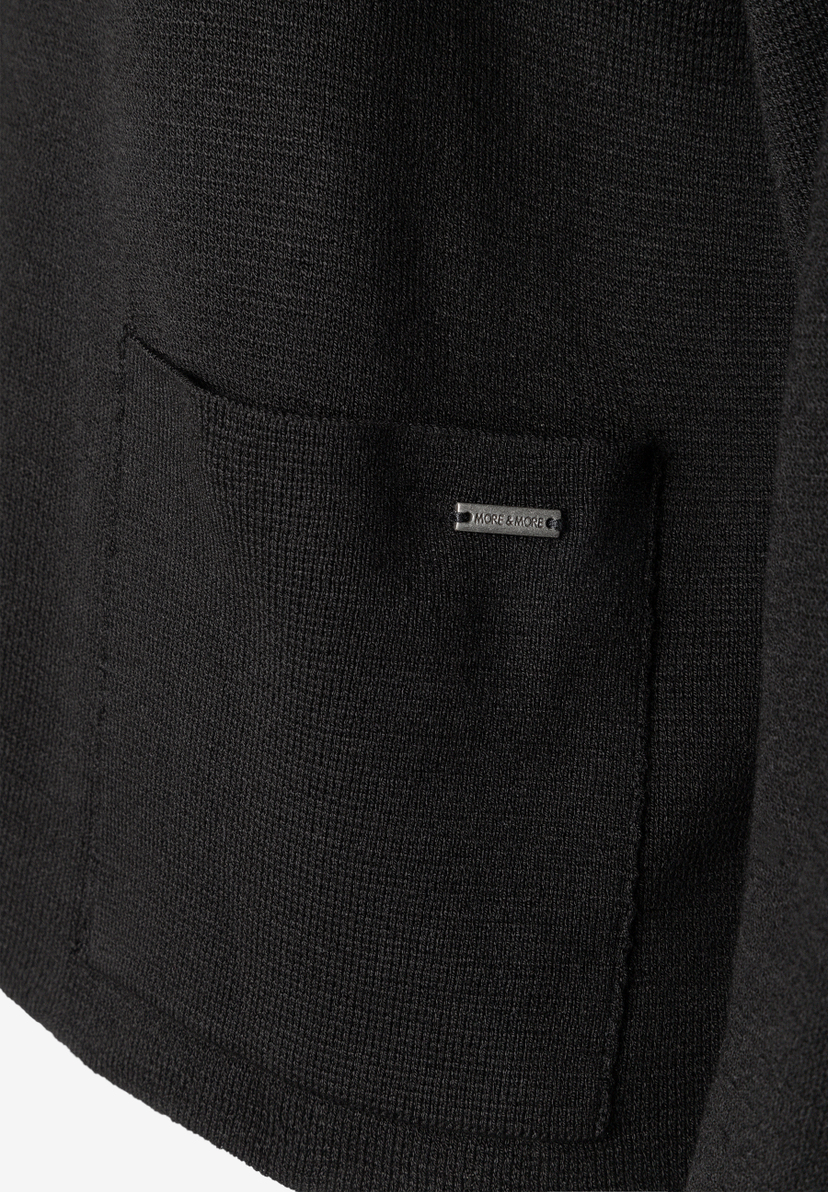 MORE & MORE Strickpullover in Schwarz. Nahaufnahme eines aufgesetzten Taschen-Details mit eingesticktem Marken-Logo.