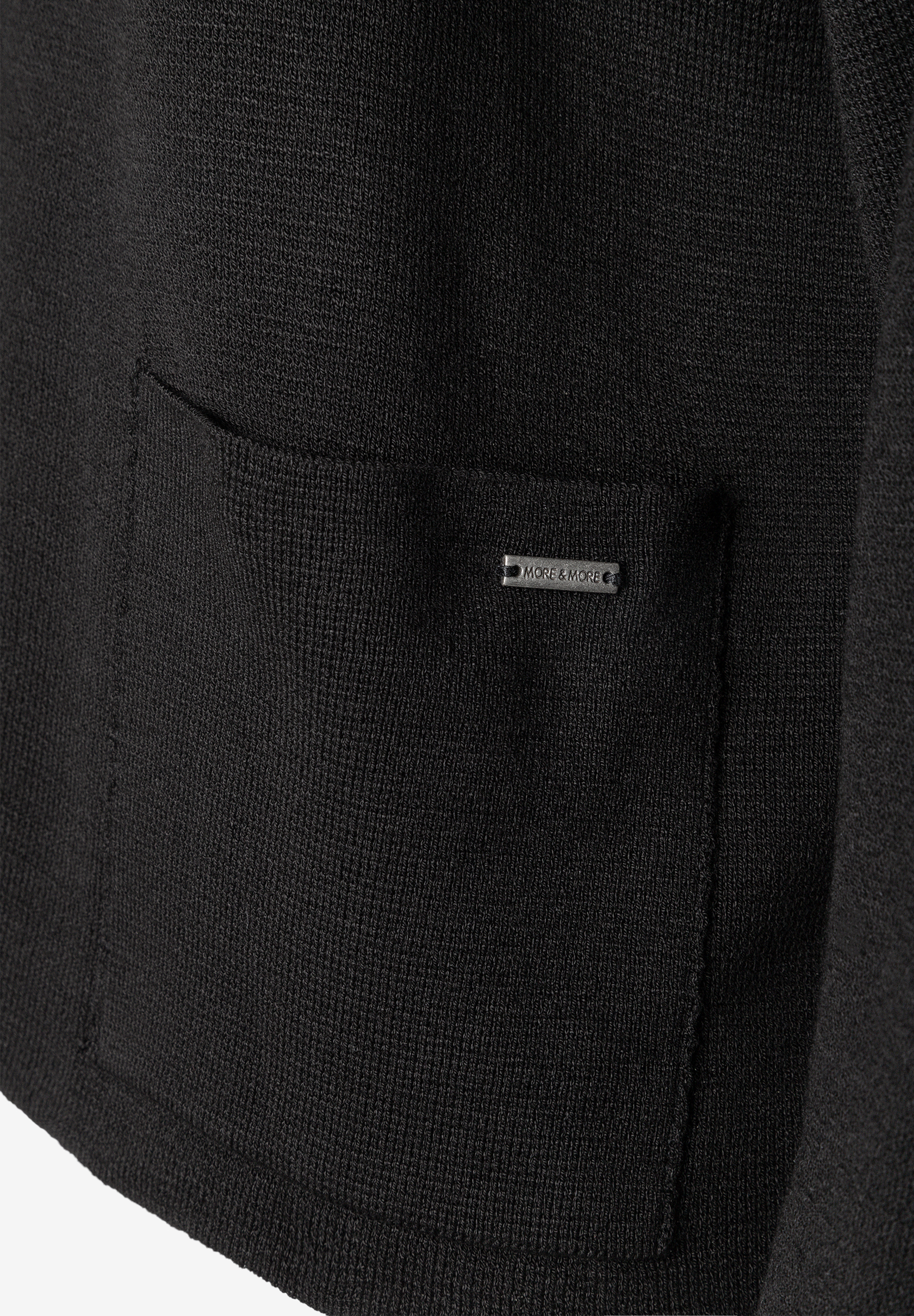 MORE & MORE Strickpullover in Schwarz. Nahaufnahme eines aufgesetzten Taschen-Details mit eingesticktem Marken-Logo. MORE & MORE Strickpullover in Schwarz. Nahaufnahme eines aufgesetzten Taschen-Details mit eingesticktem Marken-Logo.