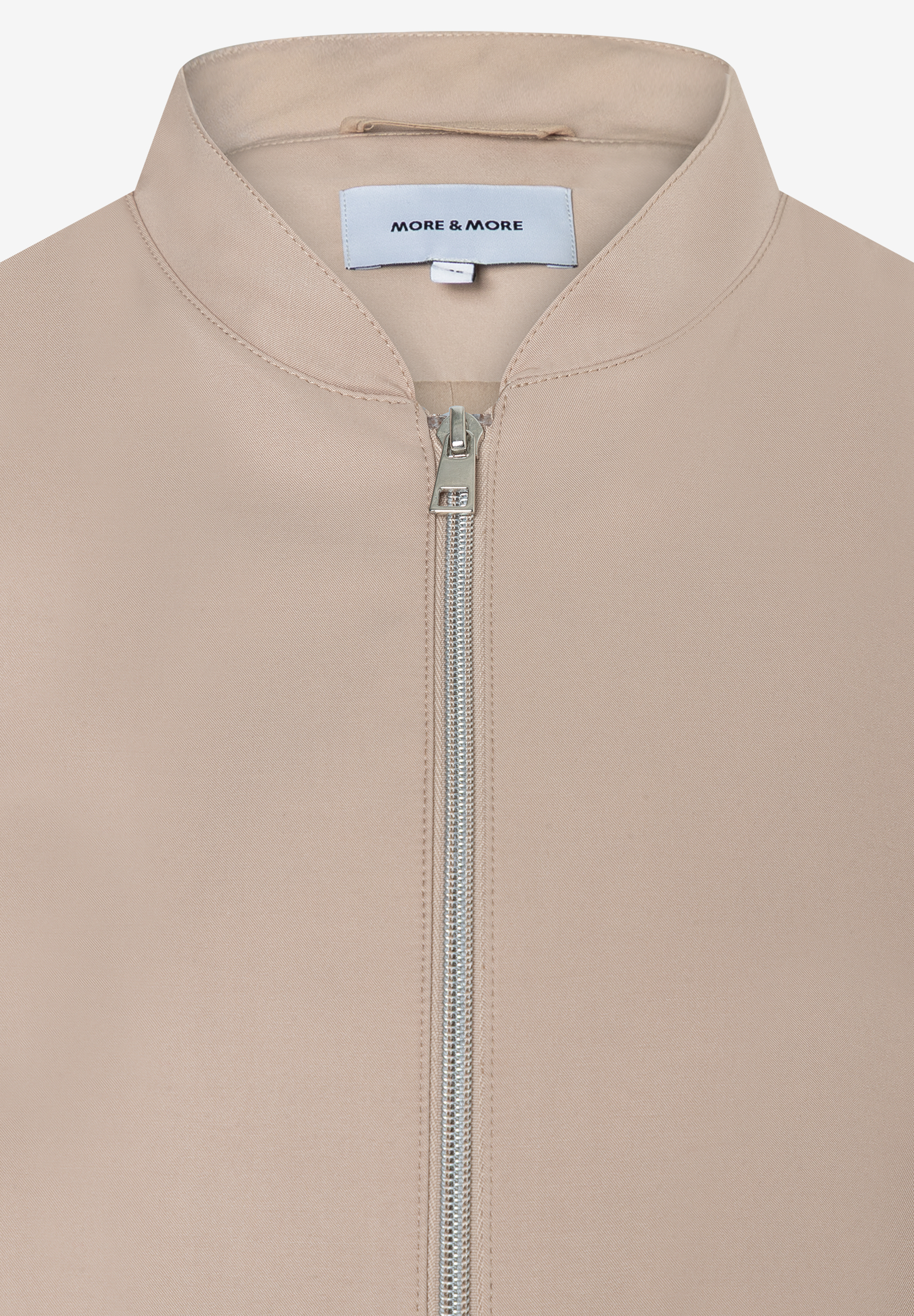 Nahaufnahme einer MORE & MORE Jacke (Webware) mit Reißverschluss und Etikett. Nahaufnahme einer MORE & MORE Jacke (Webware) mit Reißverschluss und Etikett.