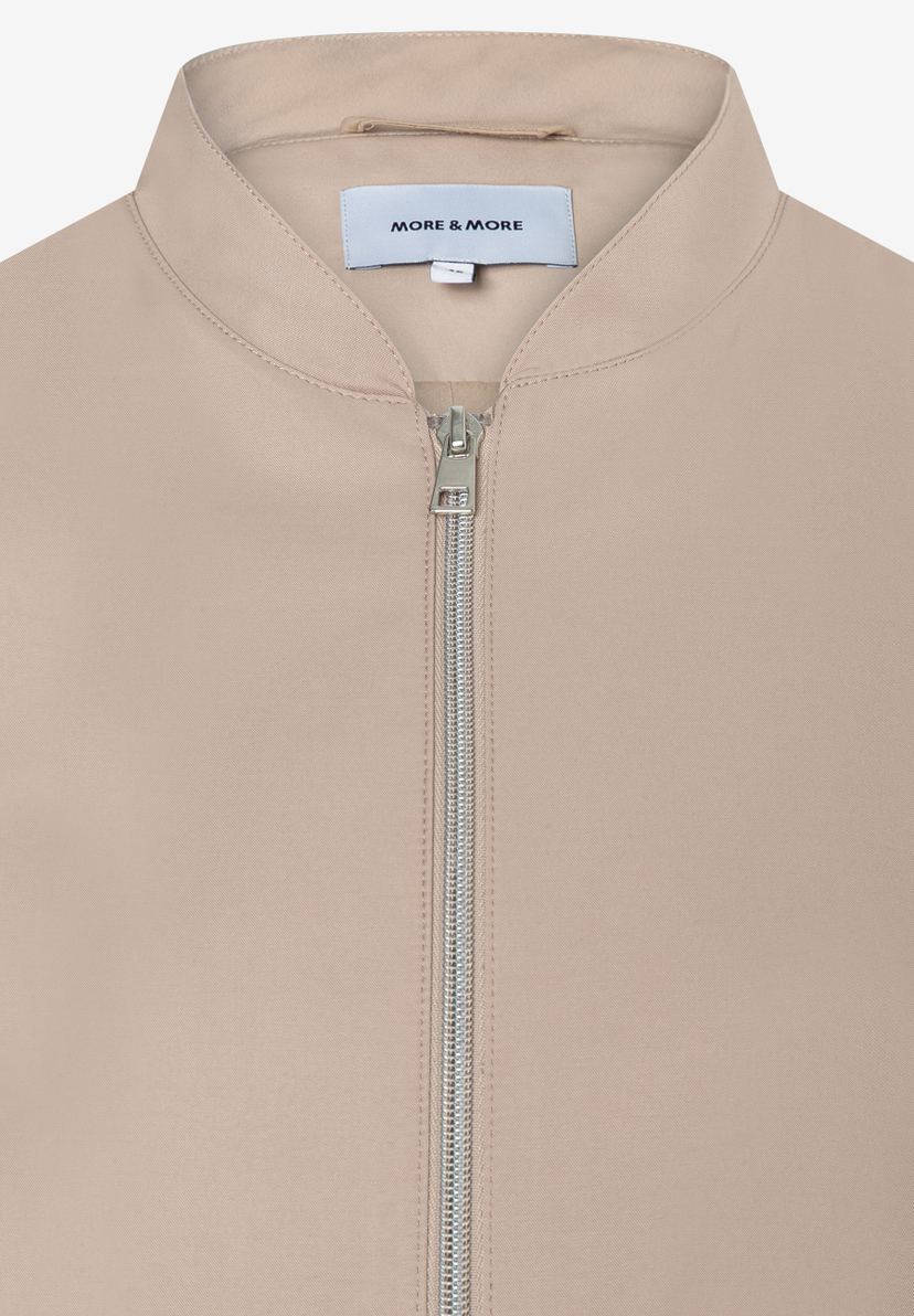 Nahaufnahme einer MORE & MORE Jacke (Webware) mit Reißverschluss und Etikett. Nahaufnahme einer MORE & MORE Jacke (Webware) mit Reißverschluss und Etikett.