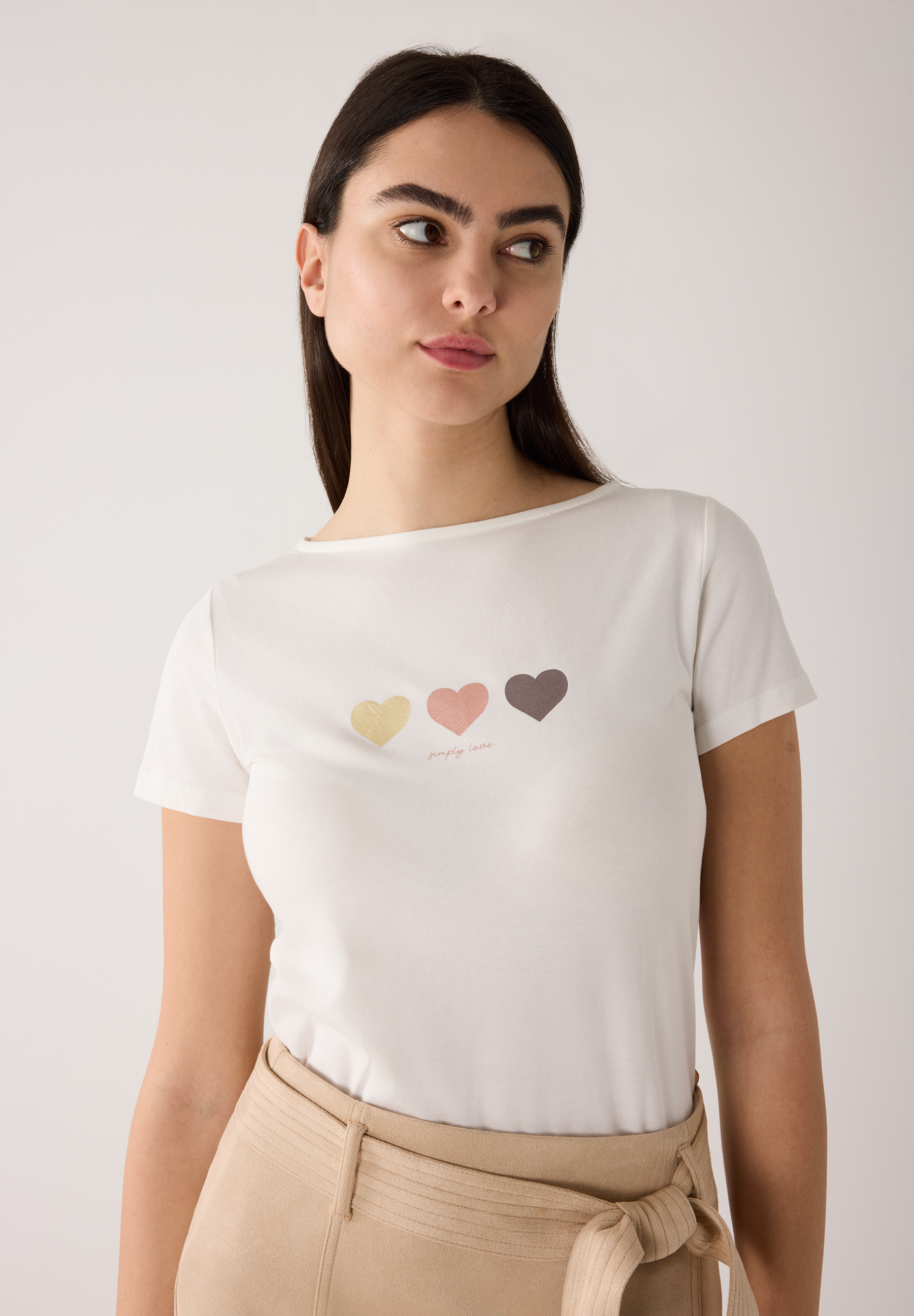 Ein weißes MORE & MORE T-Shirt mit drei Herzen und der Aufschrift "simply love" wird von einer Frau getragen.