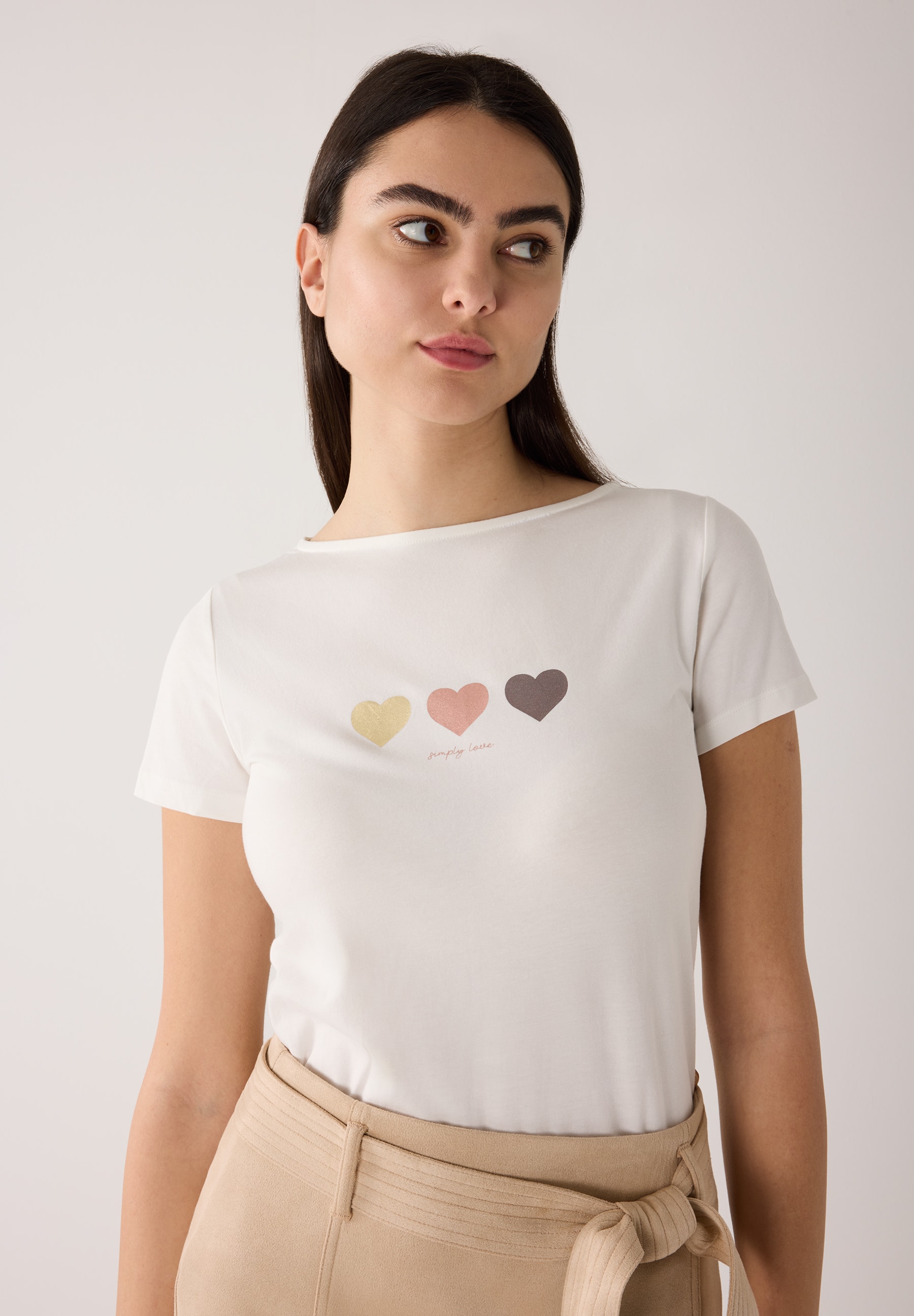 Ein weißes MORE & MORE T-Shirt mit drei Herzen und der Aufschrift "simply love" wird von einer Frau getragen.