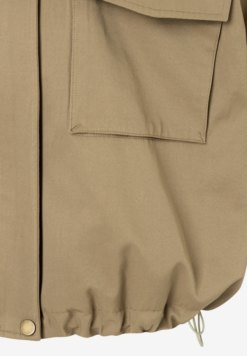 Nahaufnahme einer MORE & MORE Jacke aus Baumwollmischgewebe mit Tasche und Tunnelzug am Saum. Nahaufnahme einer MORE & MORE Jacke aus Baumwollmischgewebe mit Tasche und Tunnelzug am Saum.