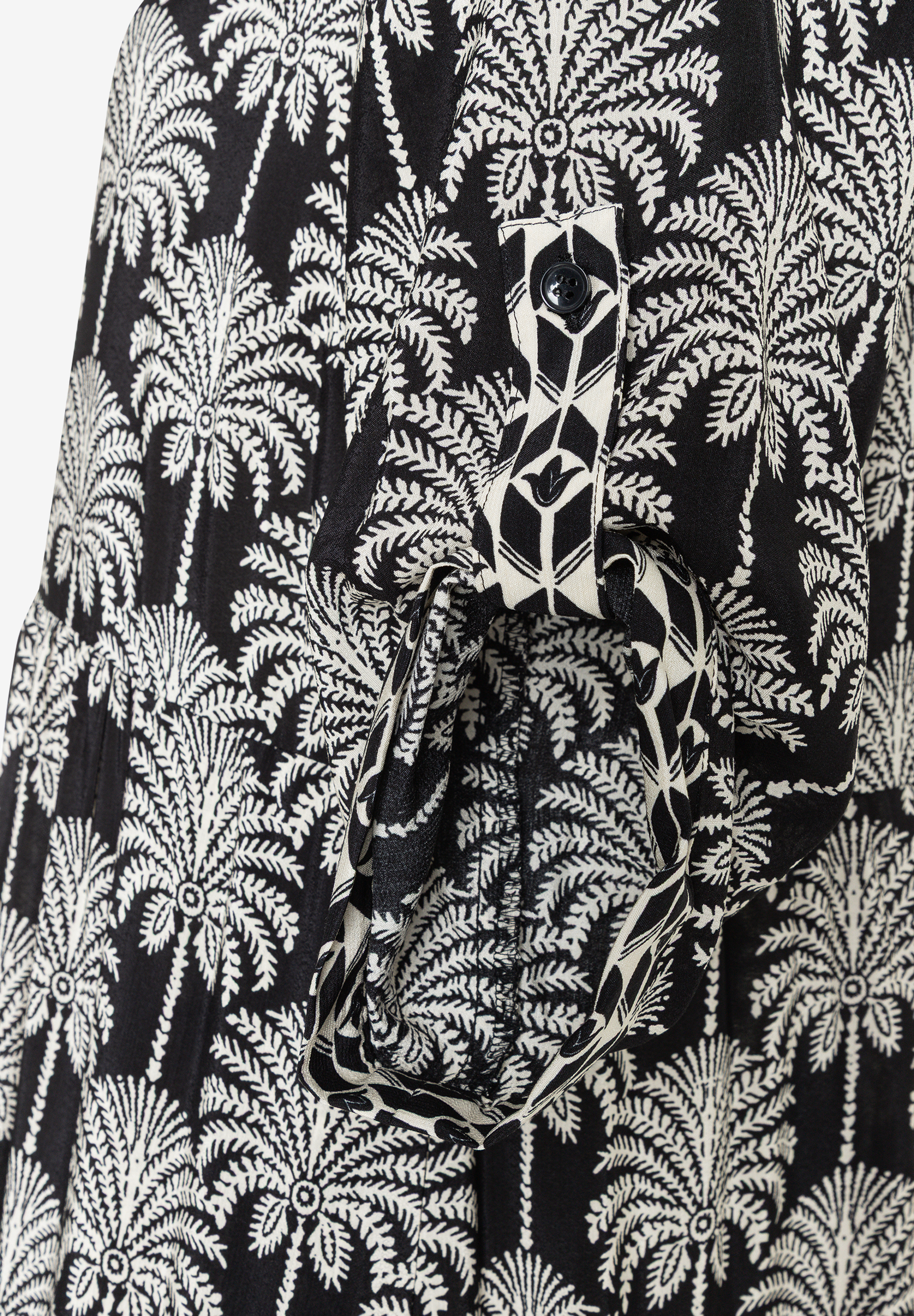 MORE & MORE Oberteil: Schwarzes Kleid mit weißen Palmen- und Blättermotiven. Ein Ärmel ist hochgekrempelt und mit einem Knopf befestigt. MORE & MORE Oberteil: Schwarzes Kleid mit weißen Palmen- und Blättermotiven. Ein Ärmel ist hochgekrempelt und mit einem Knopf befestigt.