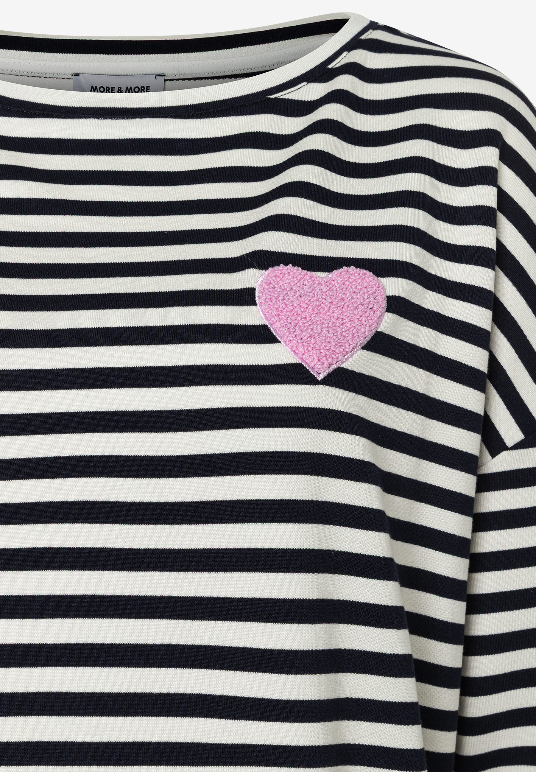 Nahaufnahme eines MORE & MORE T-Shirts mit blauen Streifen und rosafarbenem Herz auf der Brust. Nahaufnahme eines MORE & MORE T-Shirts mit blauen Streifen und rosafarbenem Herz auf der Brust.