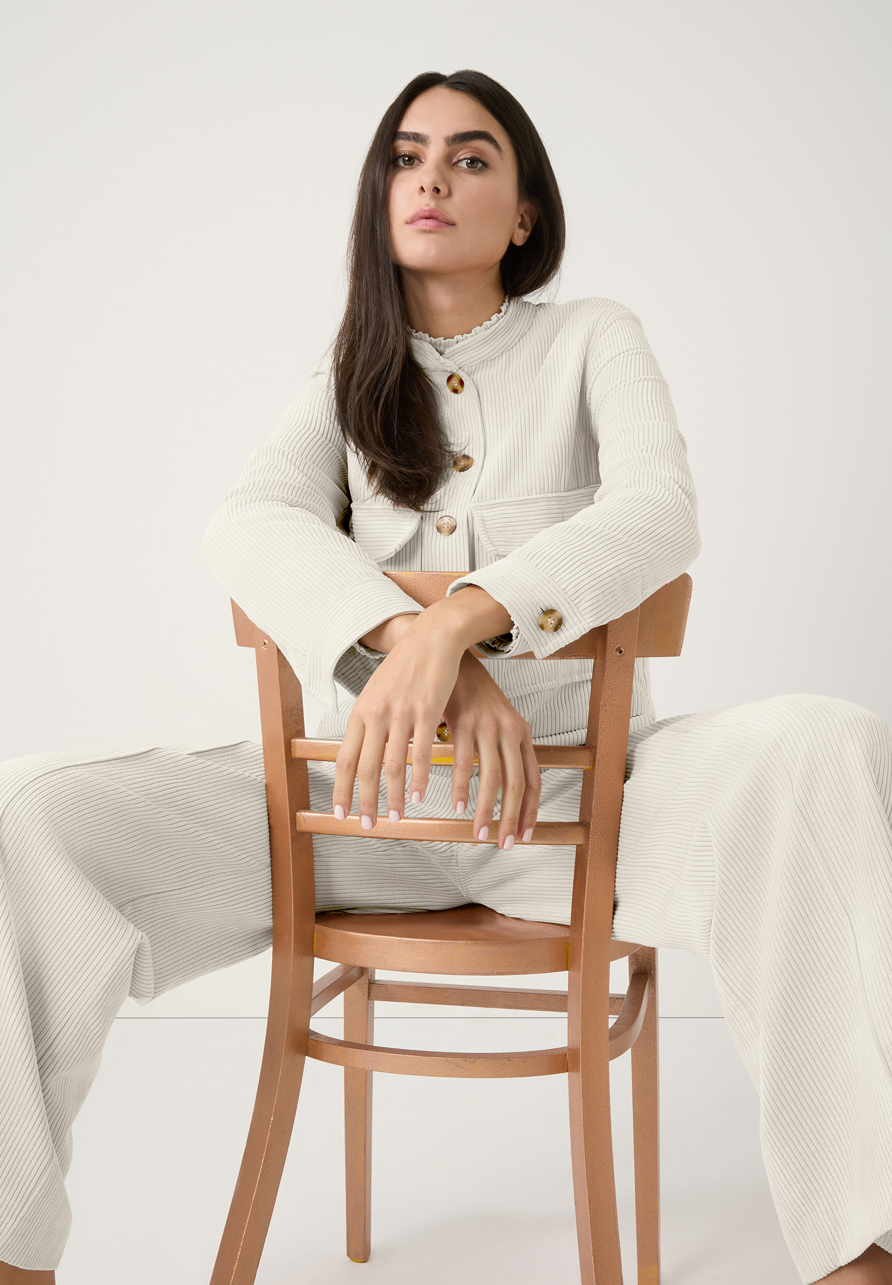 Eine Frau sitzt auf einem Stuhl und trägt ein MORE & MORE Cord-Oberteil mit bequemer, elastischer Materialkonstruktion. Eine Frau sitzt auf einem Stuhl und trägt ein MORE & MORE Cord-Oberteil mit bequemer, elastischer Materialkonstruktion.