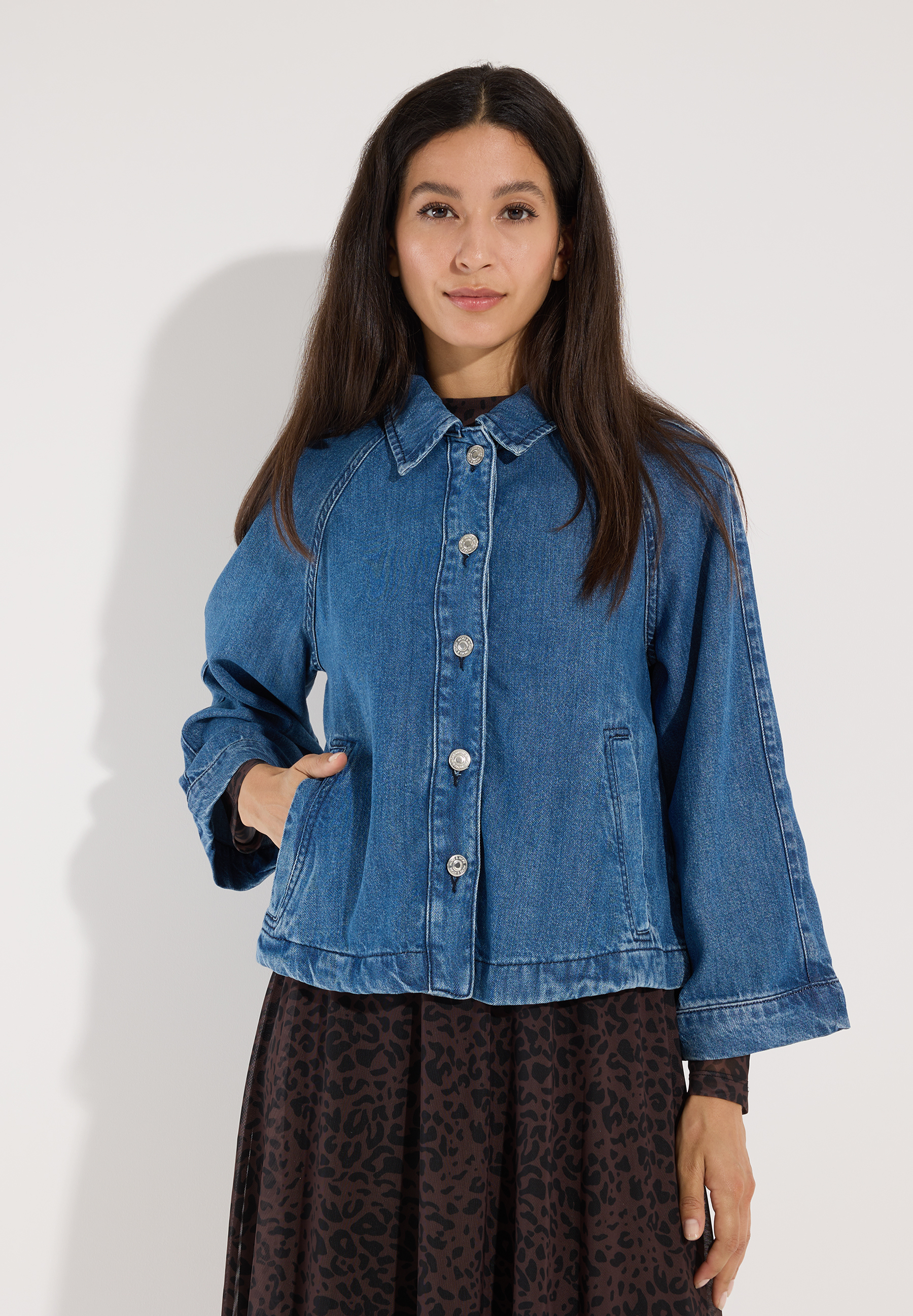 MORE & MORE Jeansjacke aus Denim mit langen Ärmeln und silbernen Knöpfen. Eine Dame trägt die Jacke über einem braun-weiß gemusterten Kleid. MORE & MORE Jeansjacke aus Denim mit langen Ärmeln und silbernen Knöpfen. Eine Dame trägt die Jacke über einem braun-weiß gemusterten Kleid.